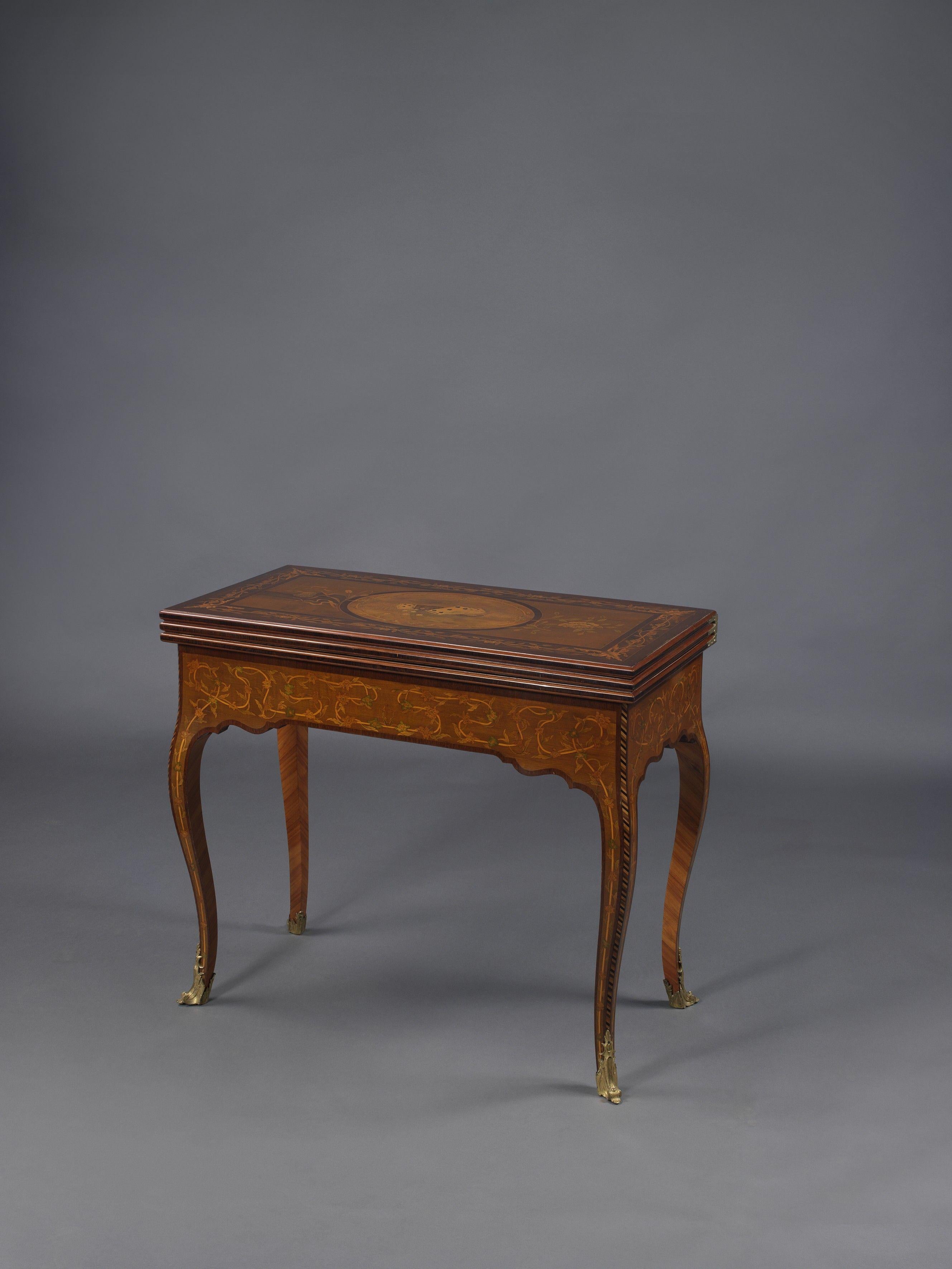 Ein seltener und höchst bedeutender, dreifach drehbarer Spieltisch aus der russischen Kaiserzeit mit Goldbronze und Intarsieneinlagen.
 
St. Petersburg, um 1820.

Dieser seltene und elegante Spieltisch mit Intarsien, auch Lomberian genannt, ist