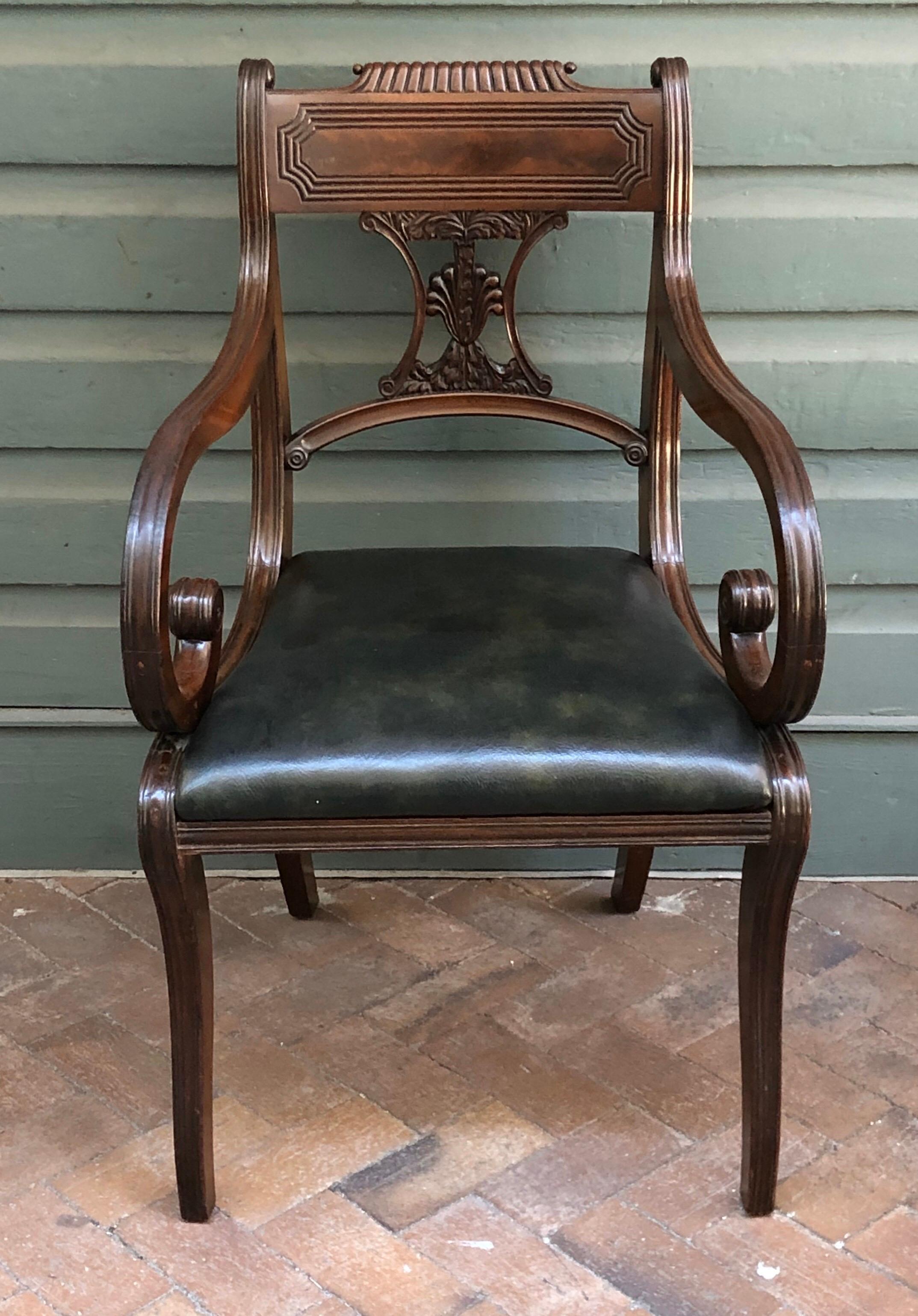 This English set of eight classical Regency saber leg chairs are crafted out solid Cuban mahogany, The backs are unusually carved with a palmetto tree splat. The exceptionally craved chairs have a beautiful reeded scroll top crest rail with reeding
