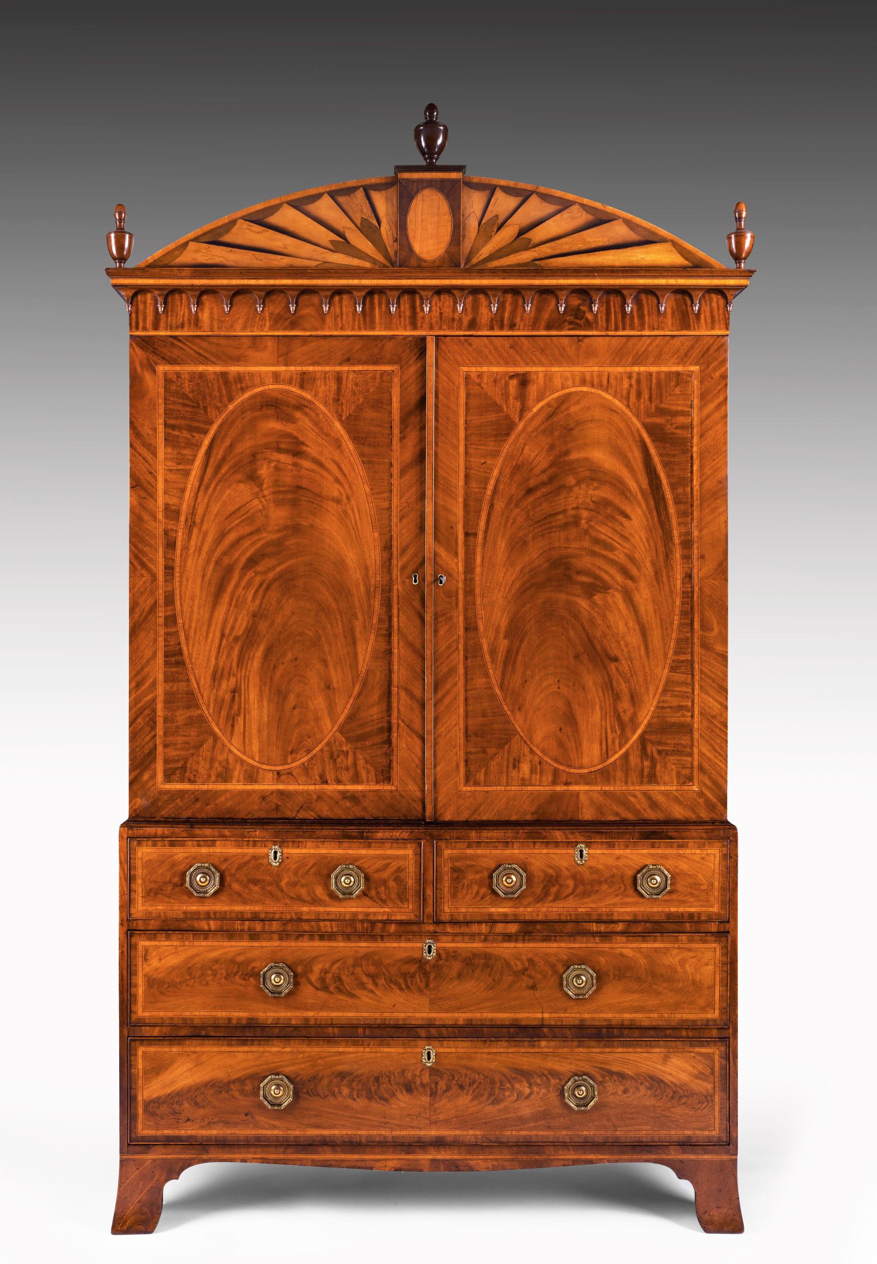 An extremely fine quality George III Sheraton period mahogany and satinwood inlaid linen press / mahogany clothes press of outstanding figuring and color, circa 1790.
The cornice having a central oval inlaid tablet with a satinwood fan inlaid