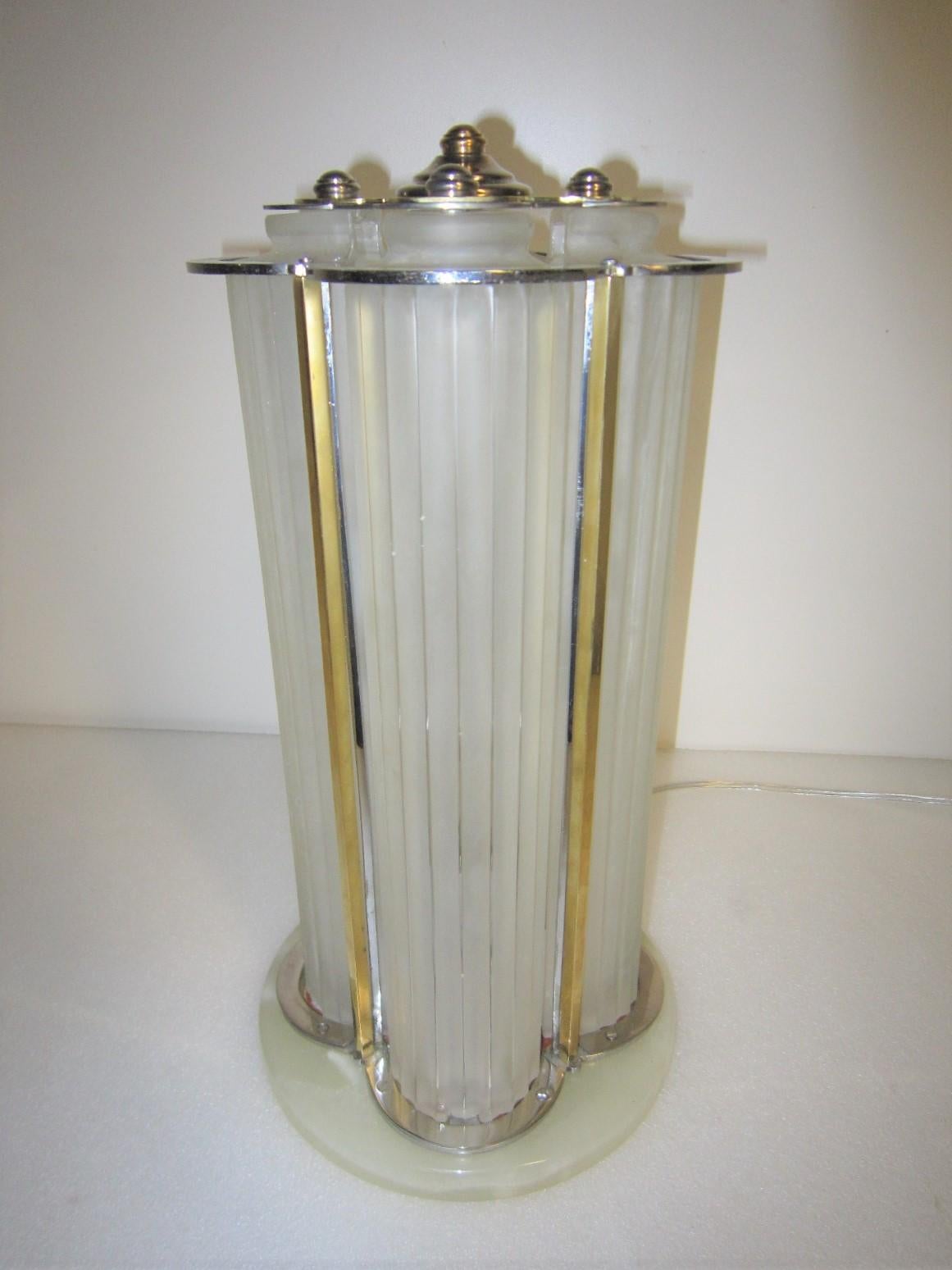 An original French Art Deco table lamp by Marius-Ernest Sabino. Four elongated fluted and frosted art glass panels in an overall clover shape grace a nickeled bronze and brass accented elegant armature that is topped by a decorative but simple