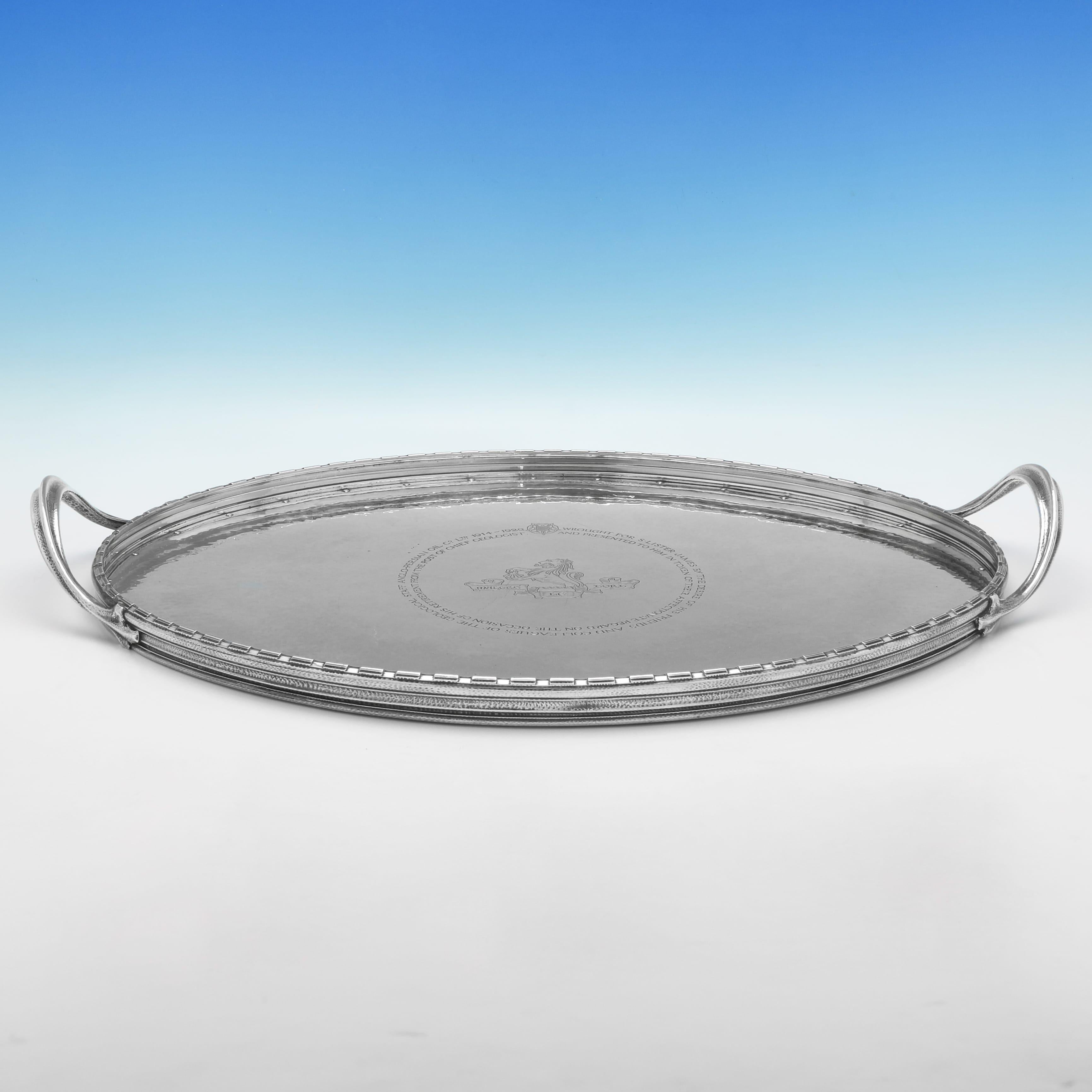 Marcada en Londres en 1929 por Omar Ramsden, esta gran bandeja de presentación de plata de ley de la época de Jorge V tiene forma ovalada, un acabado martillado y una galería elevada con un borde almenado. El centro con una inscripción de