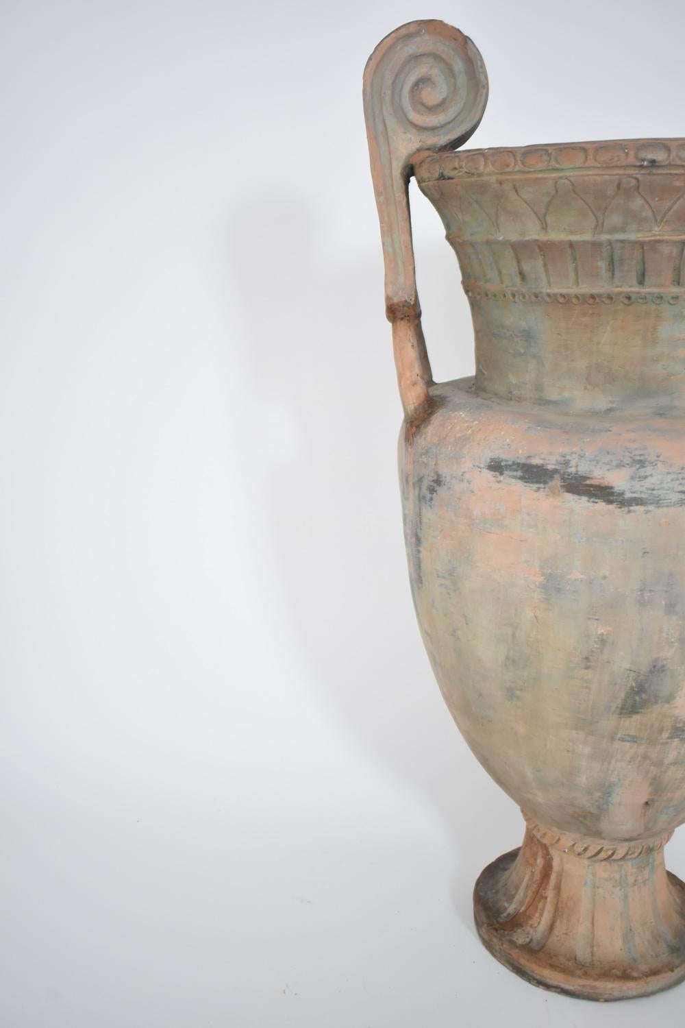 Jarrón neoclásico de crátera de terracota que se sostiene sobre un pedestal y con ormanentos geométricos grabados en el cuerpo y dos asas. Italia, década de 1910.