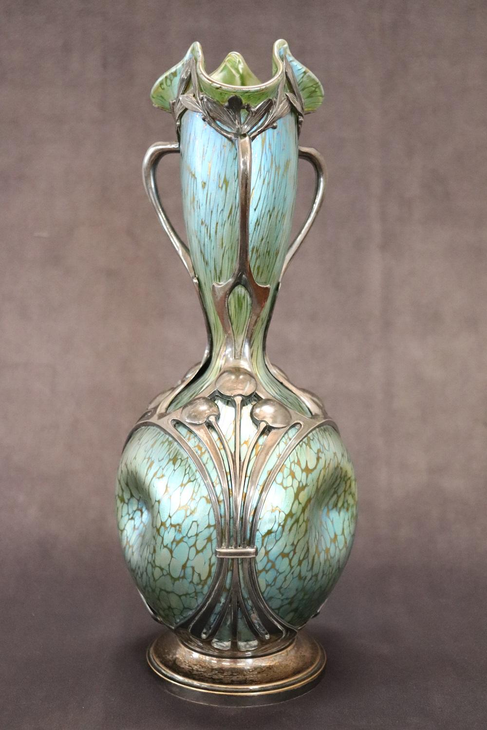 Important vase for museum display from the full Art Nouveau period. A large handled vase made of Bohemian glass with metal mount decoration in relief and chiselled in Art Nouveau style. The glass has a very particular 'Papillon' decoration; green
