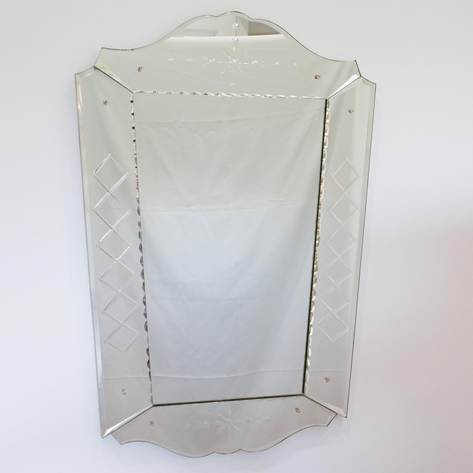 Cet extraordinaire miroir mural présente une forme de style vénitien avec des bords biseautés et un décor géométrique gravé. Cette pièce rare a été fabriquée en France vers 1940. Le flair moderniste et la forme stylisée confèrent une grande