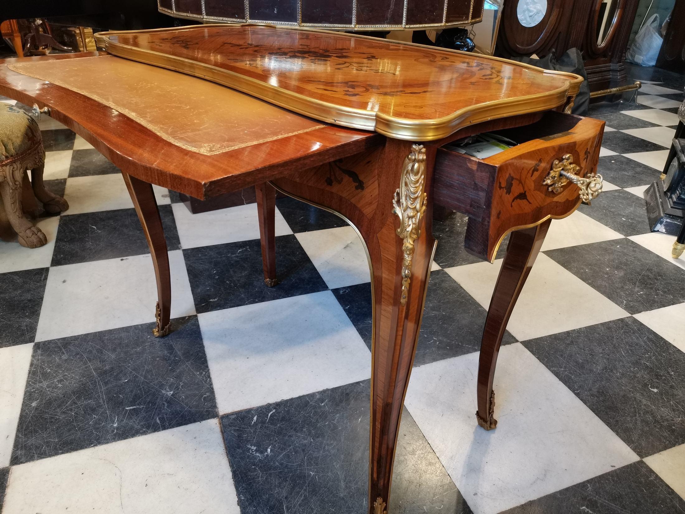 Writing table in rosewood veneer, purple wood, Amaranto,
Goodwood marquetry and gilded bronze of Louis XV era,
With a table suite of the end of the 19th century.
The tray with floral marquetry decoration in a cartridge, the belt opening to a