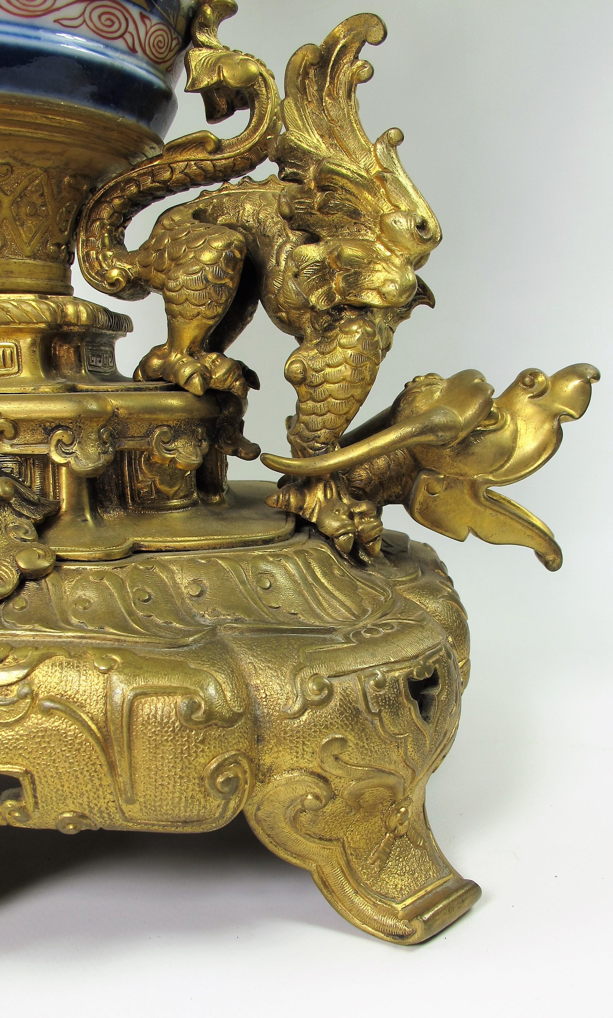 Grande pendule formée d’un vase couvert  de forme ovoïde en porcelaine d’Imari, ère Meiji période historique du Japon entre 1868 et 1912. Riche monture en bronze ciselé et doré à décor d’animaux fantastiques, chien de Fô à l’amortissement qui
