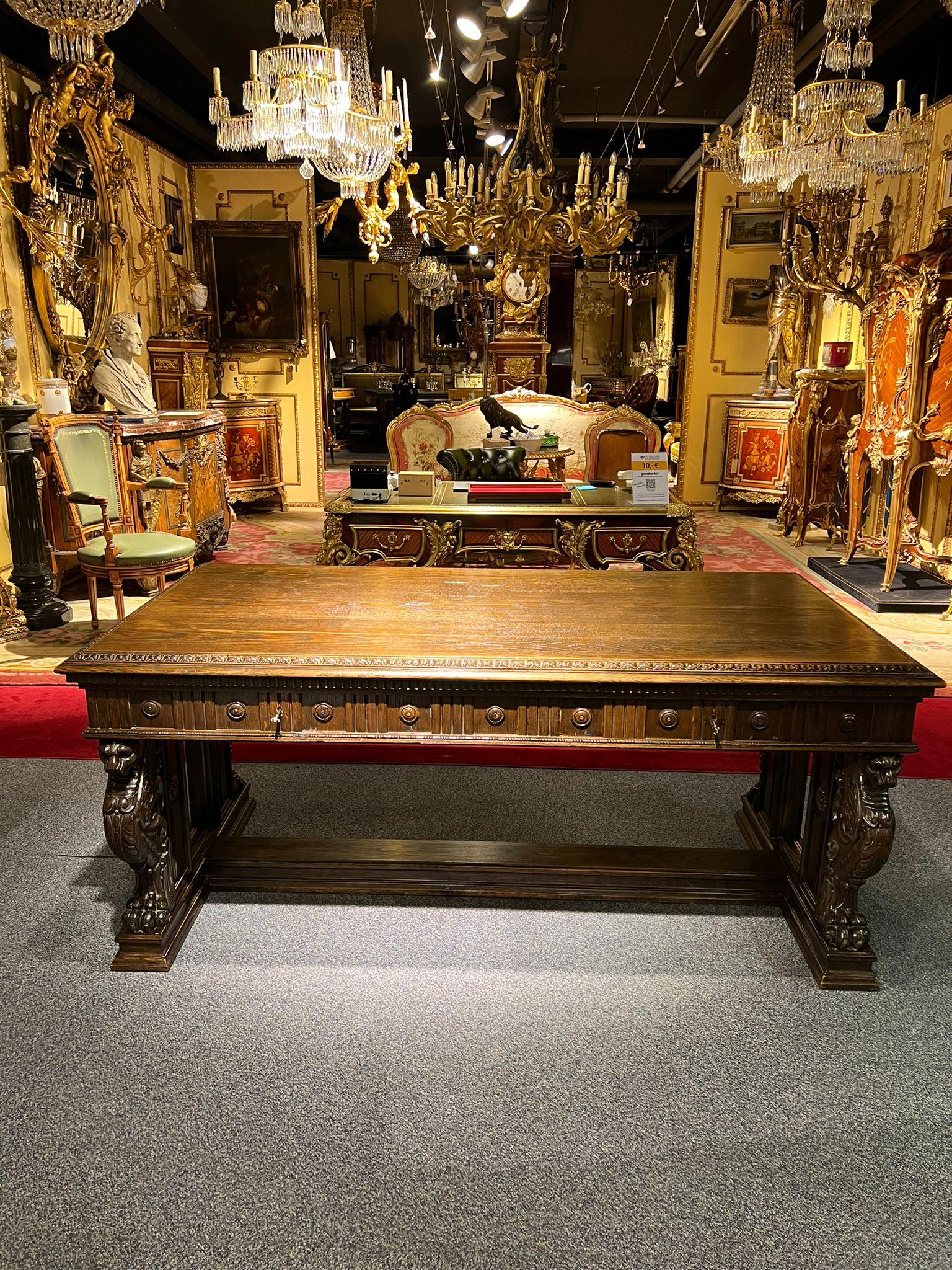Oakwood. Straight body ending on curly, Lion-shaped legs. Richly carved on all sides. Slightly protruding tabletop, including the middle drawer. The desk can be placed free in the room.
 