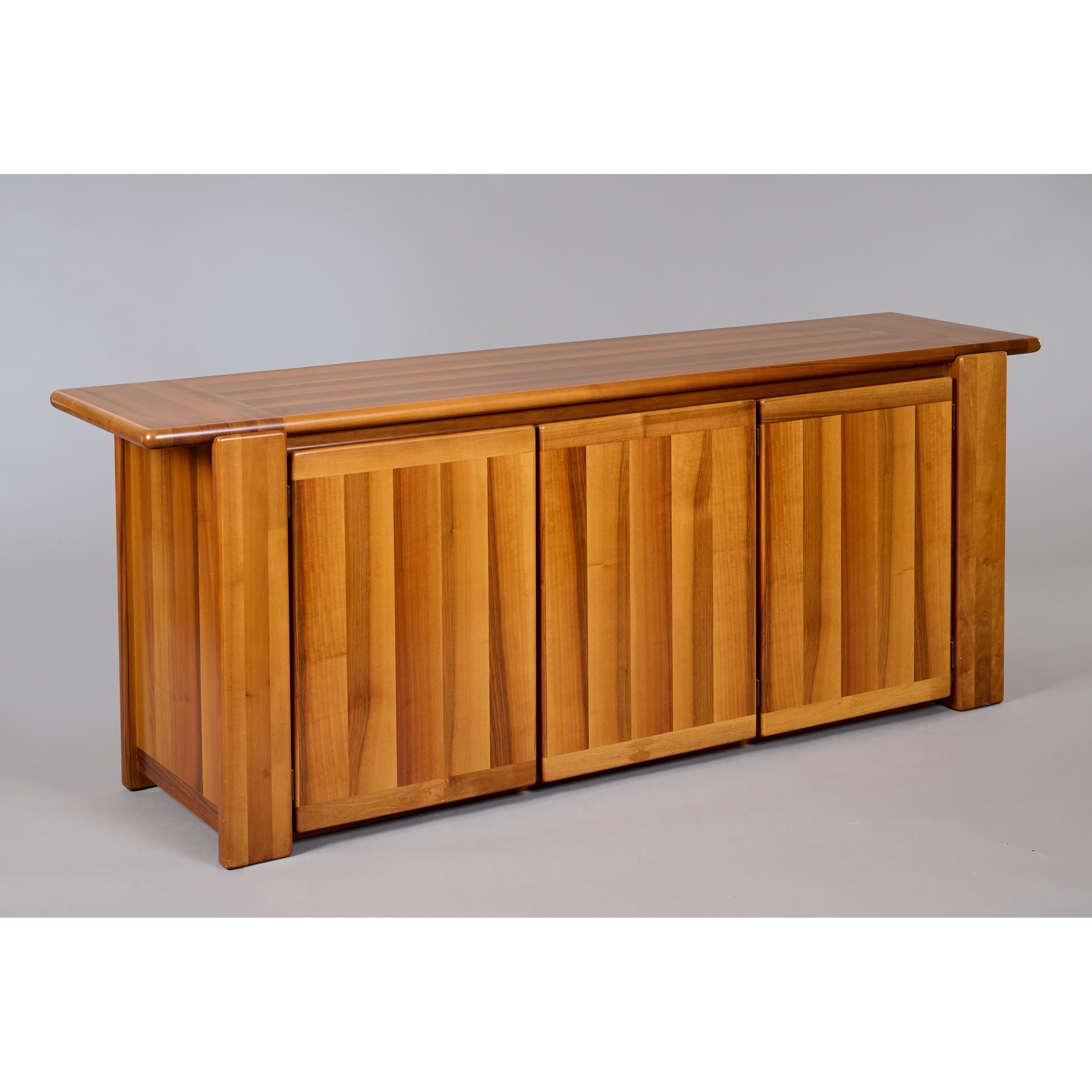 Italy, 1970's

A beautifully crafted Italian sideboard in polished walnut in the manner of woodworker Pierre Chapo, with an elongated overhang and three doors concealing capacious storage and shelving. The strikingly veneered top is striated both
