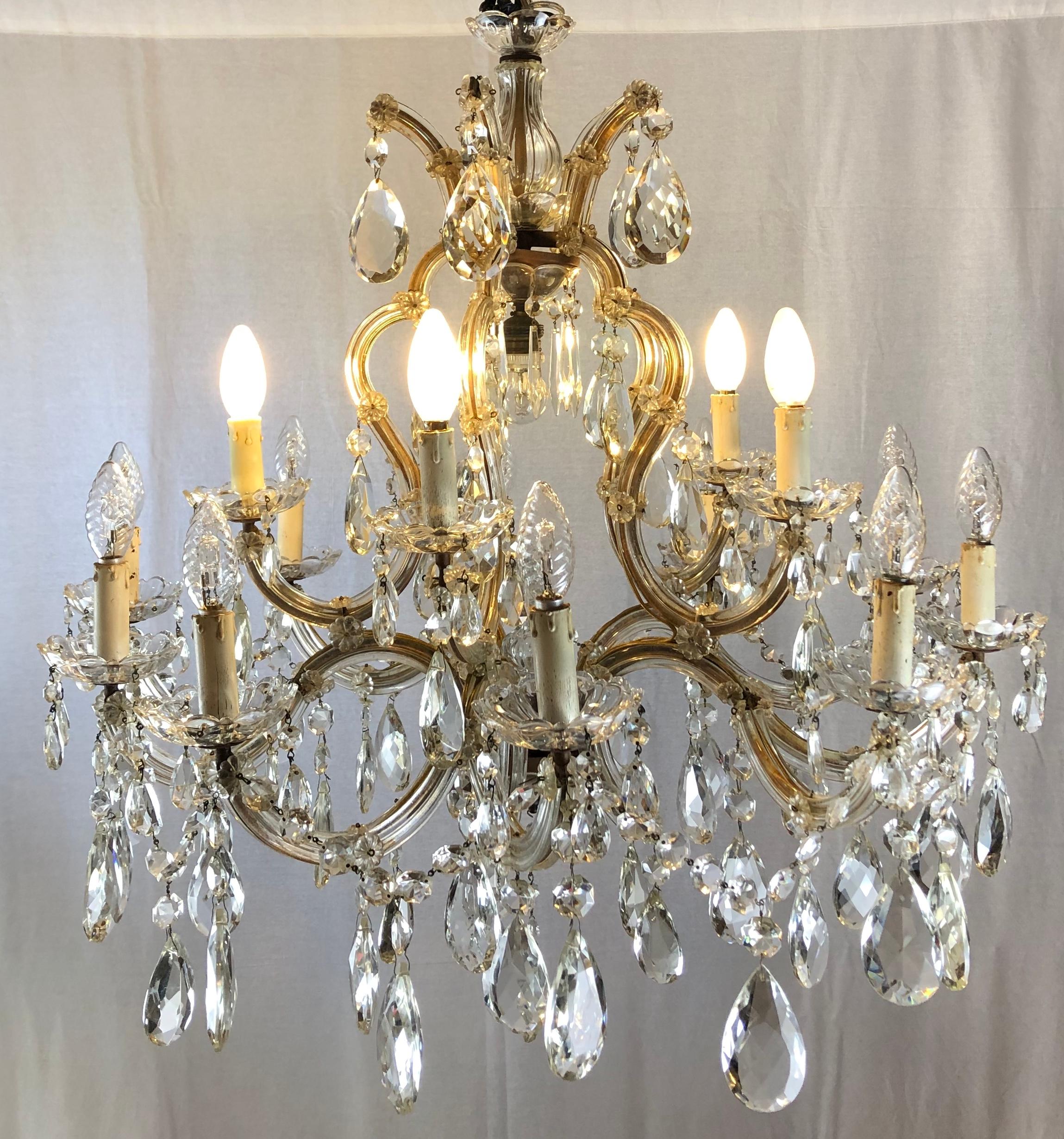 A large French Maria Theresa sixteen-light chandelier or ceiling light of faceted crystal, cut glass and gilt metal featuring serpentine arms, each candle light features floral designed glass, dangling pendants and decorative bobeche.

Beautiful