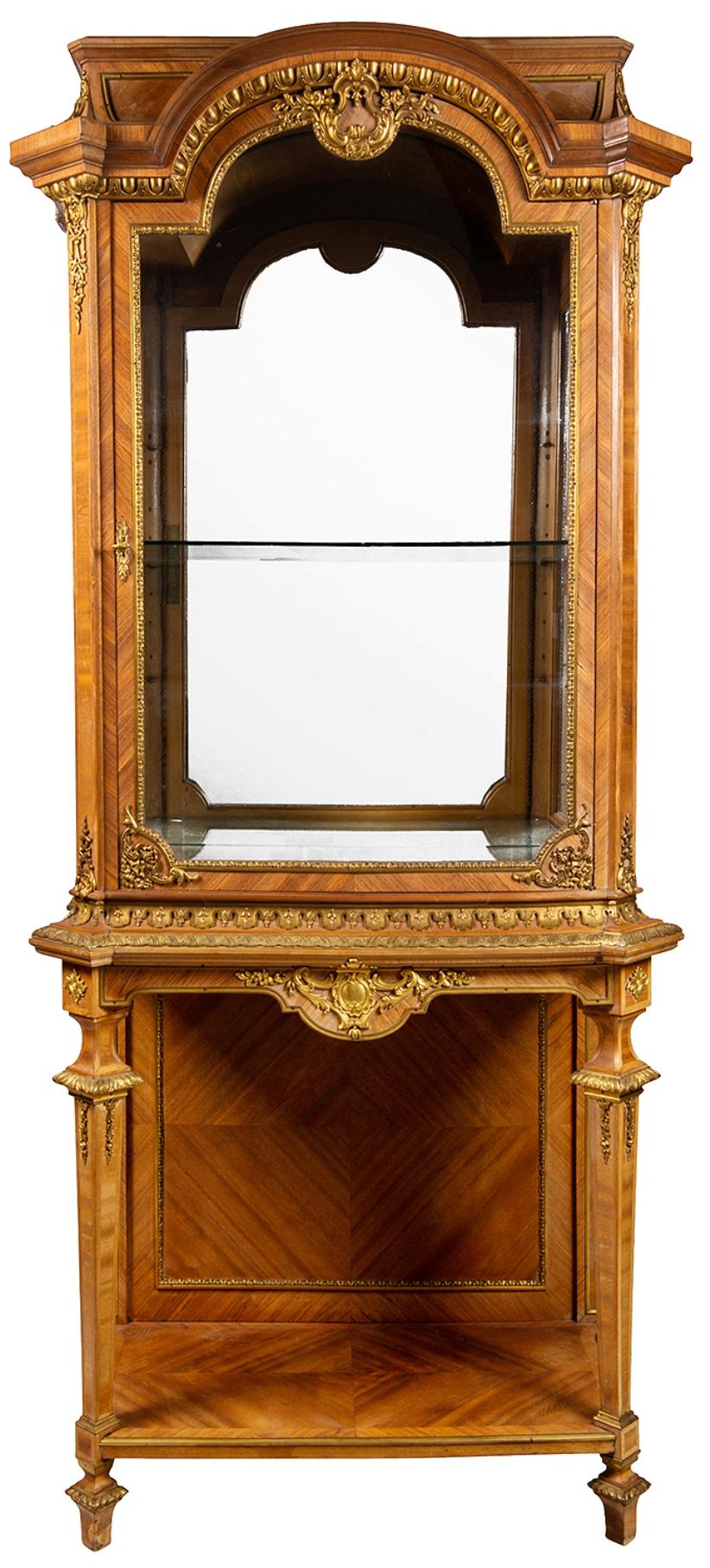 Un'imponente vetrina francese del XIX secolo in noce con ormolatura. Ha un'anta vetrata ad arco con modanatura a uovo e dardo, che si apre per rivelare un ripiano in vetro e un retro a specchio. Sopra due supporti affusolati quadrati nella parte