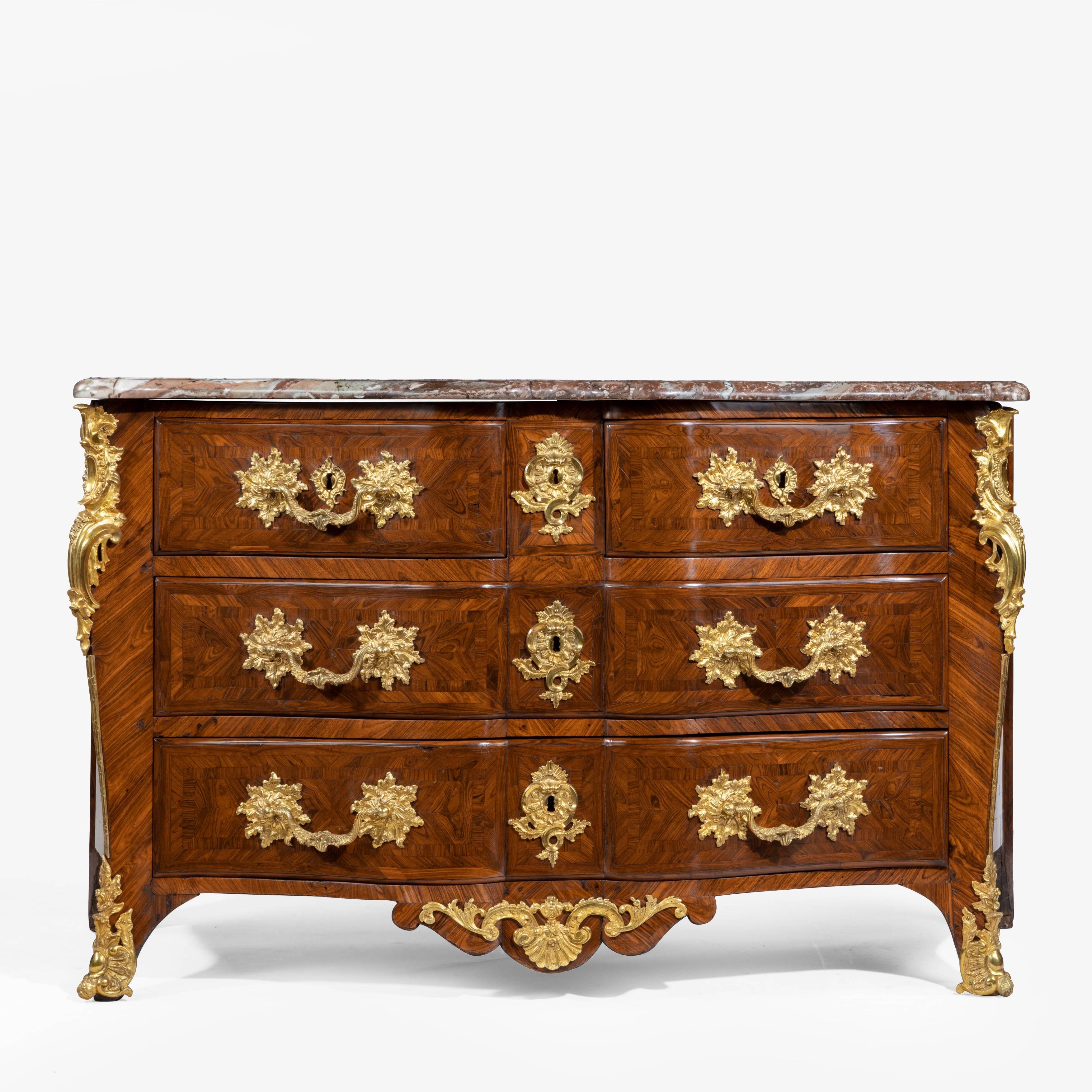 An imposing kingwood commode by de Jeune, the original rouge marble top set upon the shaped base with three wide serpentine drawers, decorated throughout with crossbanding and chevron, herring-bone and quarter-veneers, richly applied with