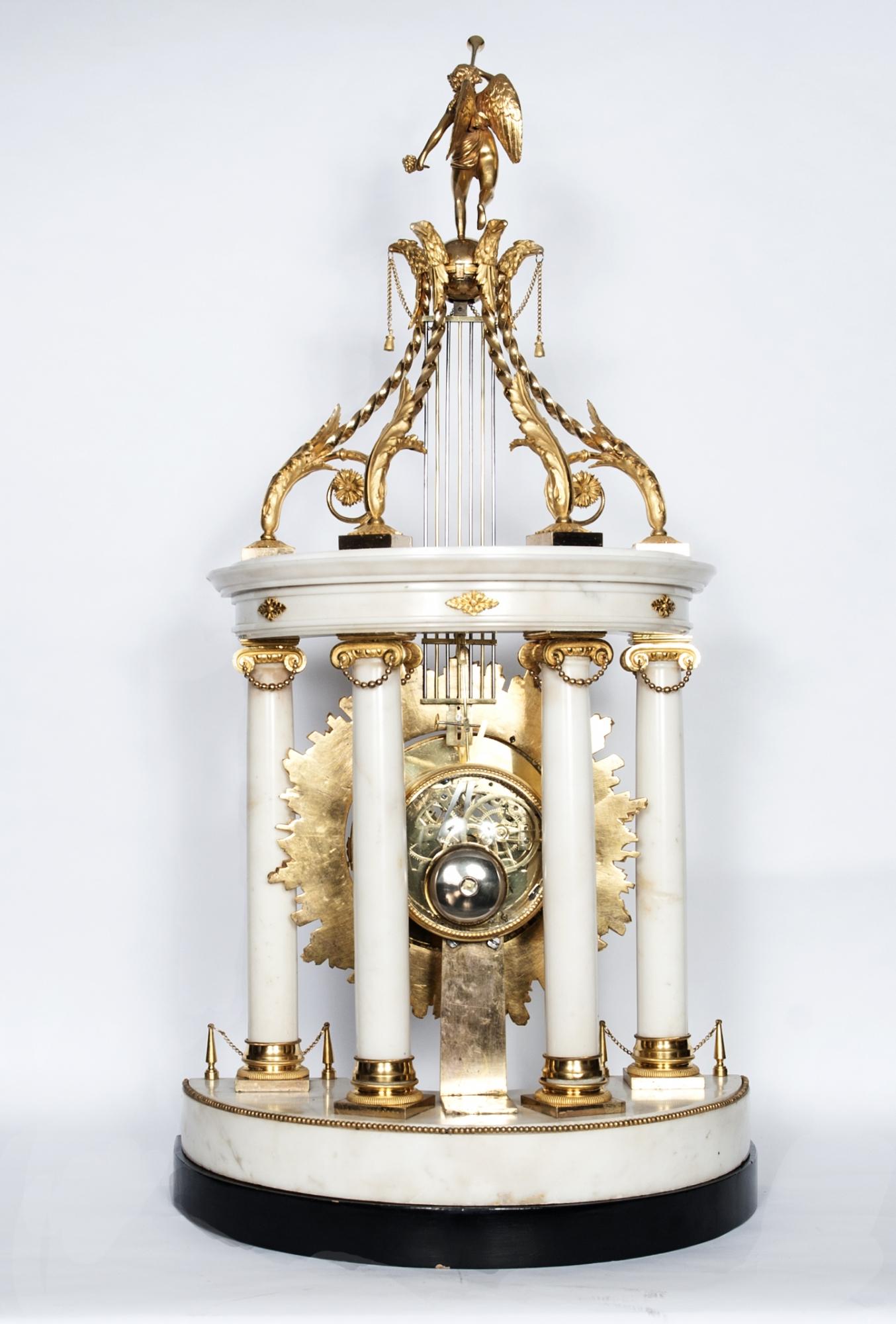 Imposante pendule de cheminée monumentale de style Louis XVI, avec pendule oscillant en forme de soleil, entouré de strass en cristal et surmonté d'un ange féminin avec trompette. Le magnifique mouvement squeletté avec date et seconde au centre.