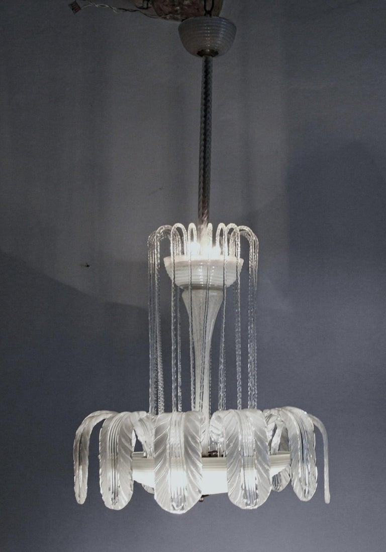 Sophisticated chandelier from Ercole Barovier.
A rare beautiful chandelier, the bottom bowl is in horizontal ribbed hand opened clear etched glass crowned by a set of 12 large and heavy leaves that are to resemble waves with foam. The puligoso
