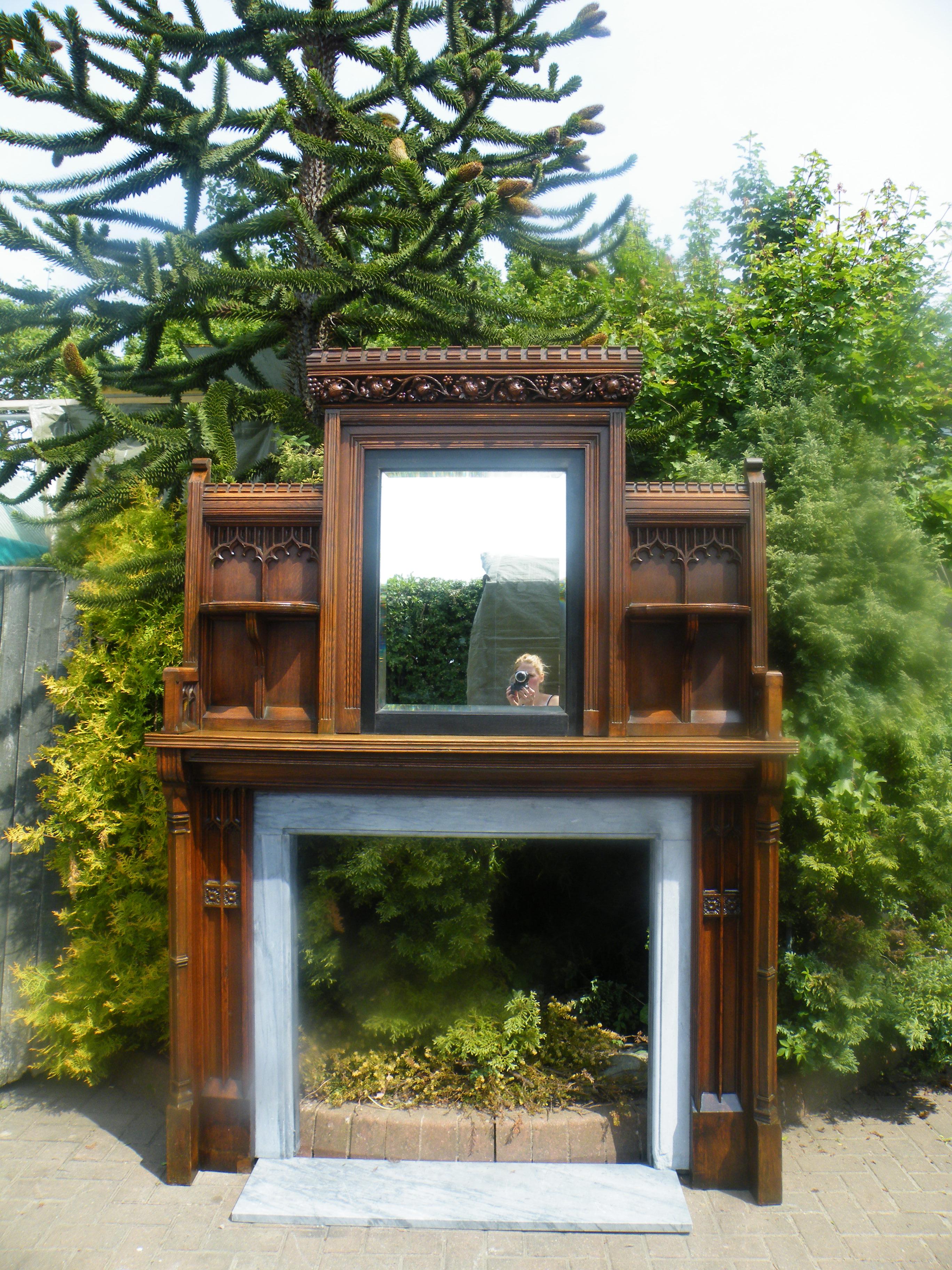 An imposing Reformed Gothic oak fireplace mantel surround 1870s with mirror in the manner of A.W.N Pugin. 

Modern Gothic, also known as Reformed Gothic, was an Aesthetic Movement style of the 1860s and 1870s in architecture, furniture and