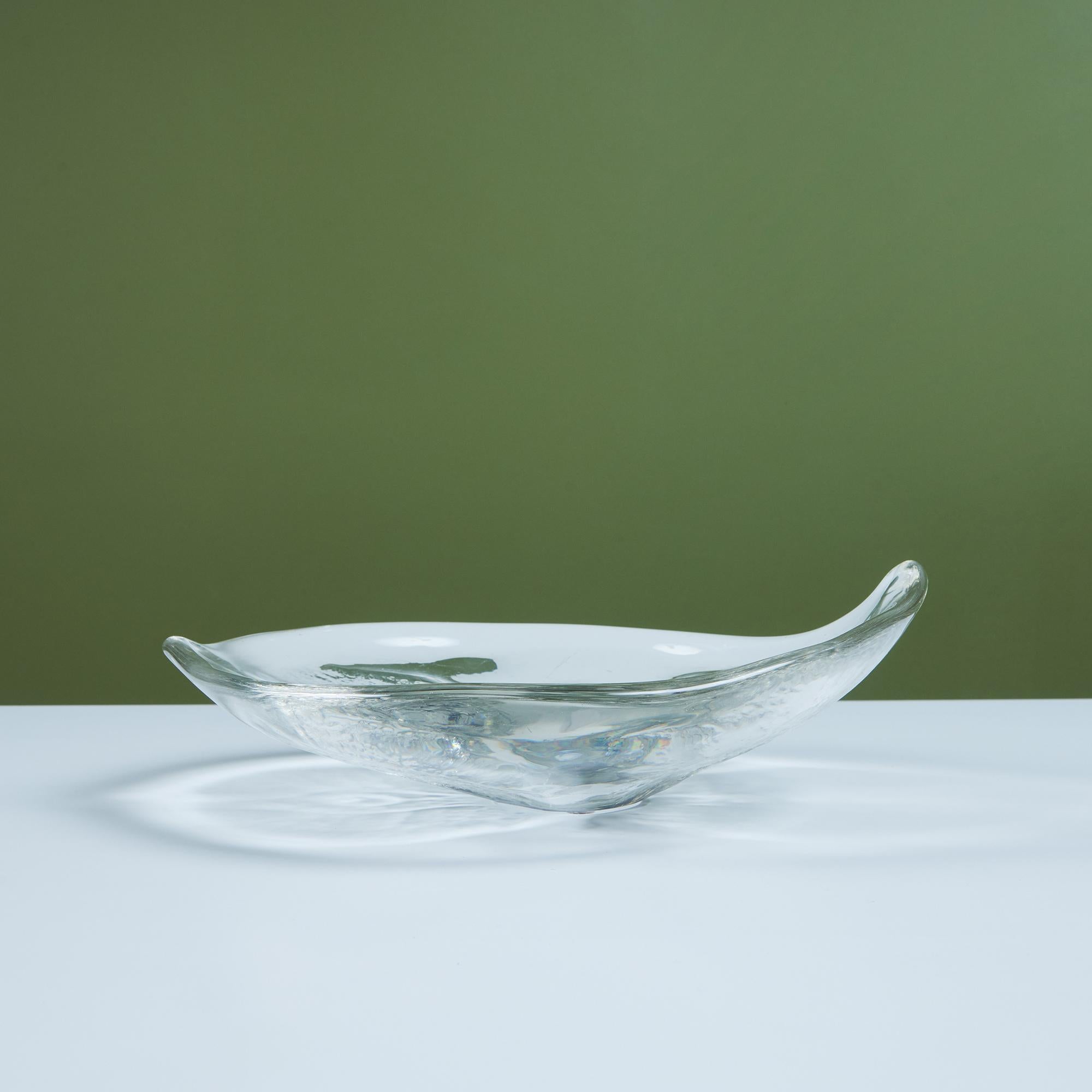 Round glass bowl features a sleek body that tapers towards two sides. The underside of the bowl is impressed with a leaf like design. 
Signed - on the bottom.

Dimensions
11.5