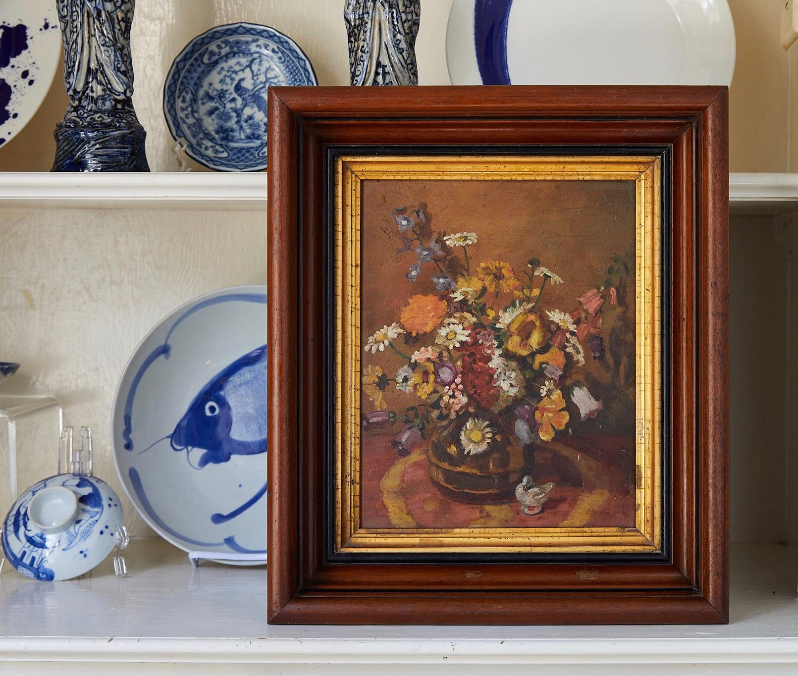 Early 20th century still life of wildflowers in a vase with a white duck figurine on the table in the foreground. The unsigned oil on board is painted in the manner of Impressionism and is held in an antique mahogany frame with gilt wood liner. The