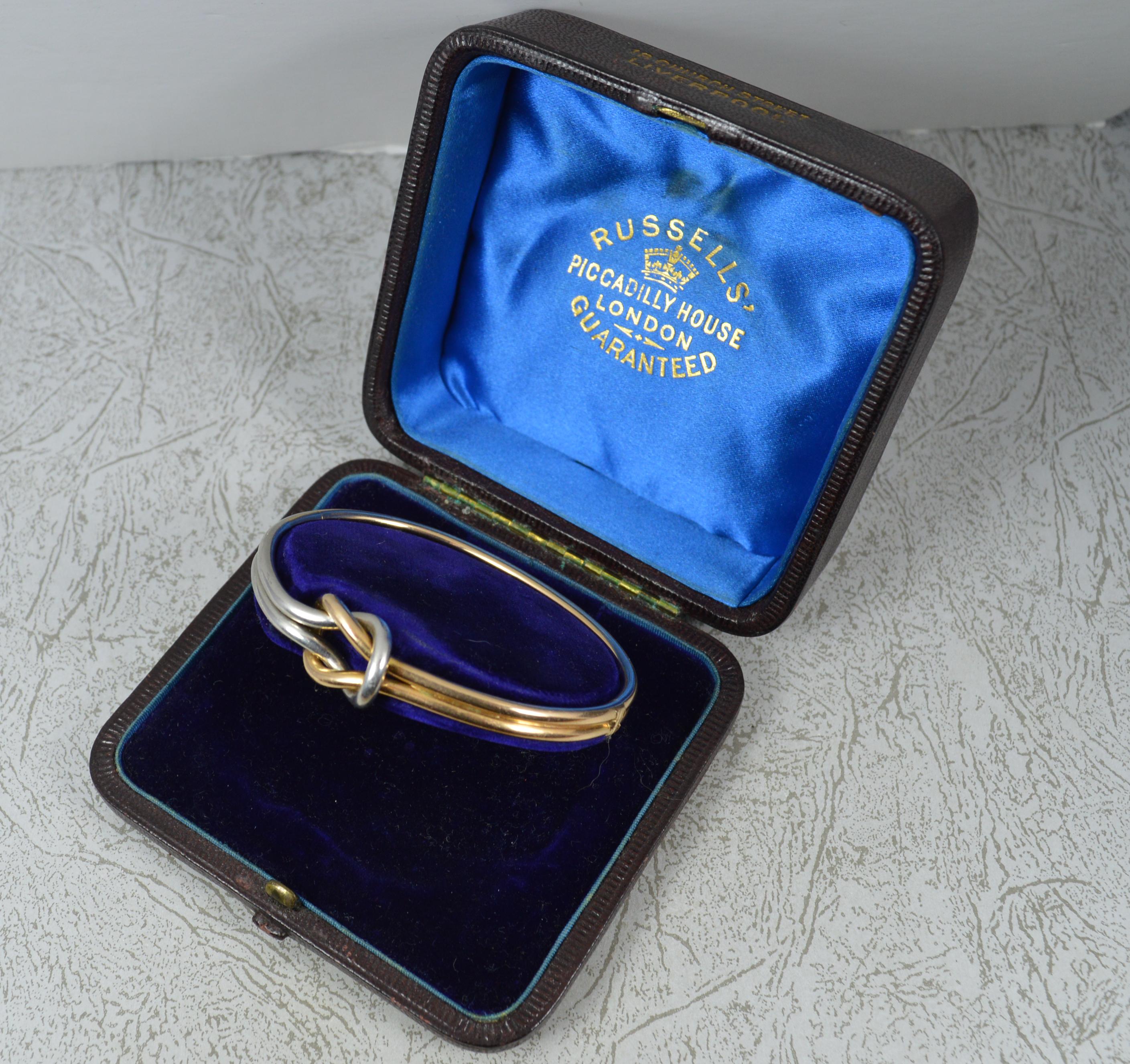 A superb Victorian period bangle. c1860-80
Modelled in a solid 14/5 carat gold bangle throughout with one quarter in platinum.
A double tube design which comes to the centre to create a forever love knot. 
Complete in a Russells leather fitted