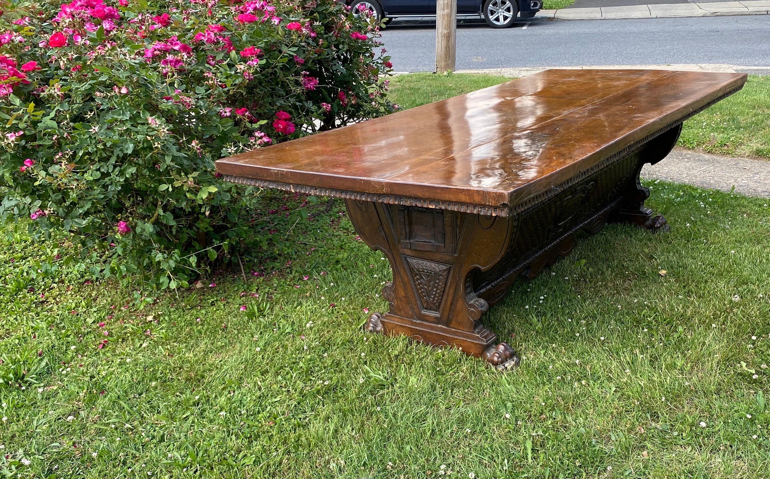 Impressive 17th century Tuscan baroque solid walnut dining or refractory table. Two solid walnut board top over a carved base with coat of arms and 2 tabernacle drawers on the sides resting on heavy, masculine paw feet. The color and patina on this