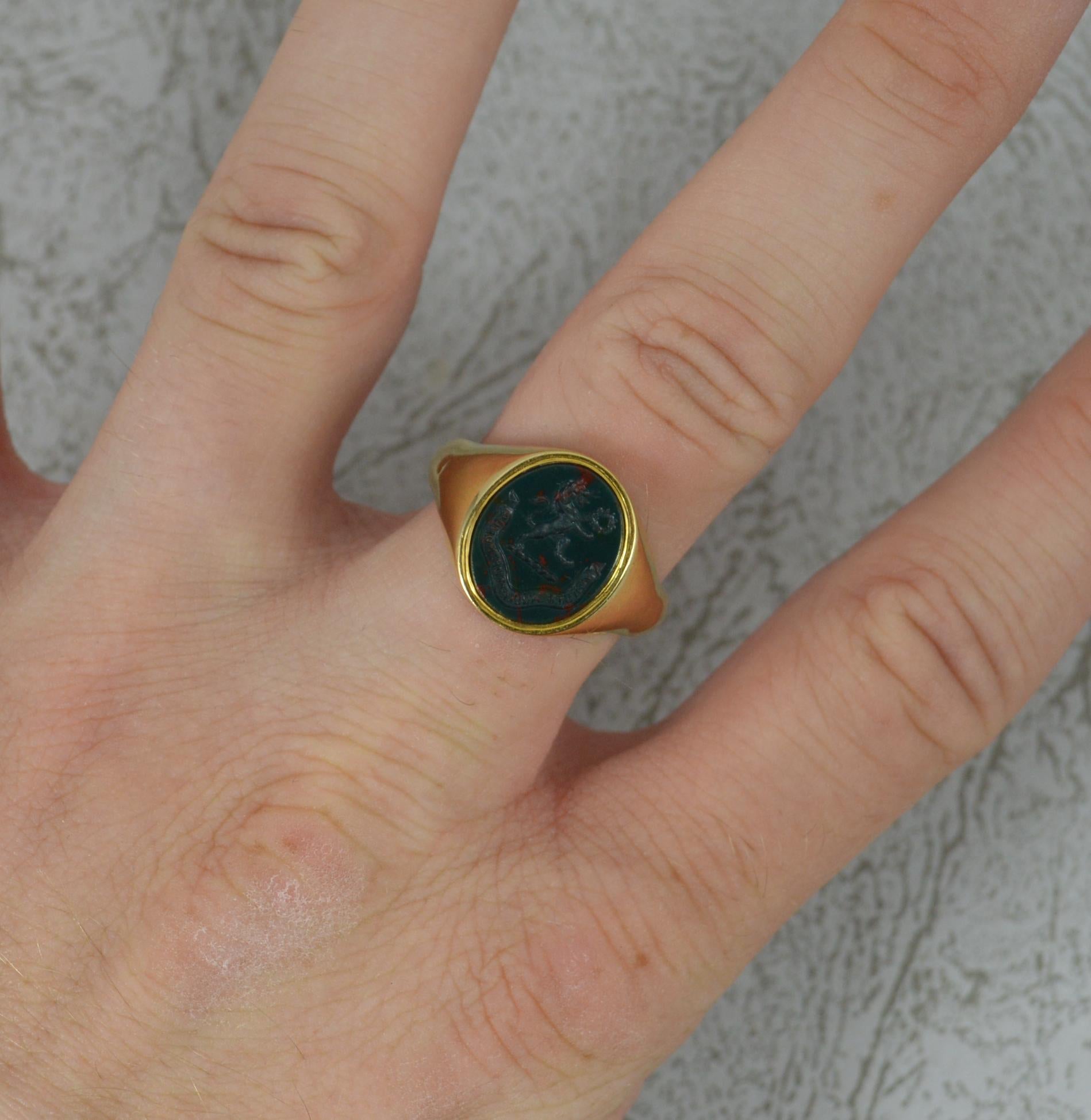 A stunning antique signet ring.
Solid 18 carat yellow gold example.
Designed with an oval shaped bloodstone. 10.6mm x 12.5mm approx.
Expertly hand carved depicting a lion passant holding a wreath. Below reads the moto Virtute Acquiritur Honos. The