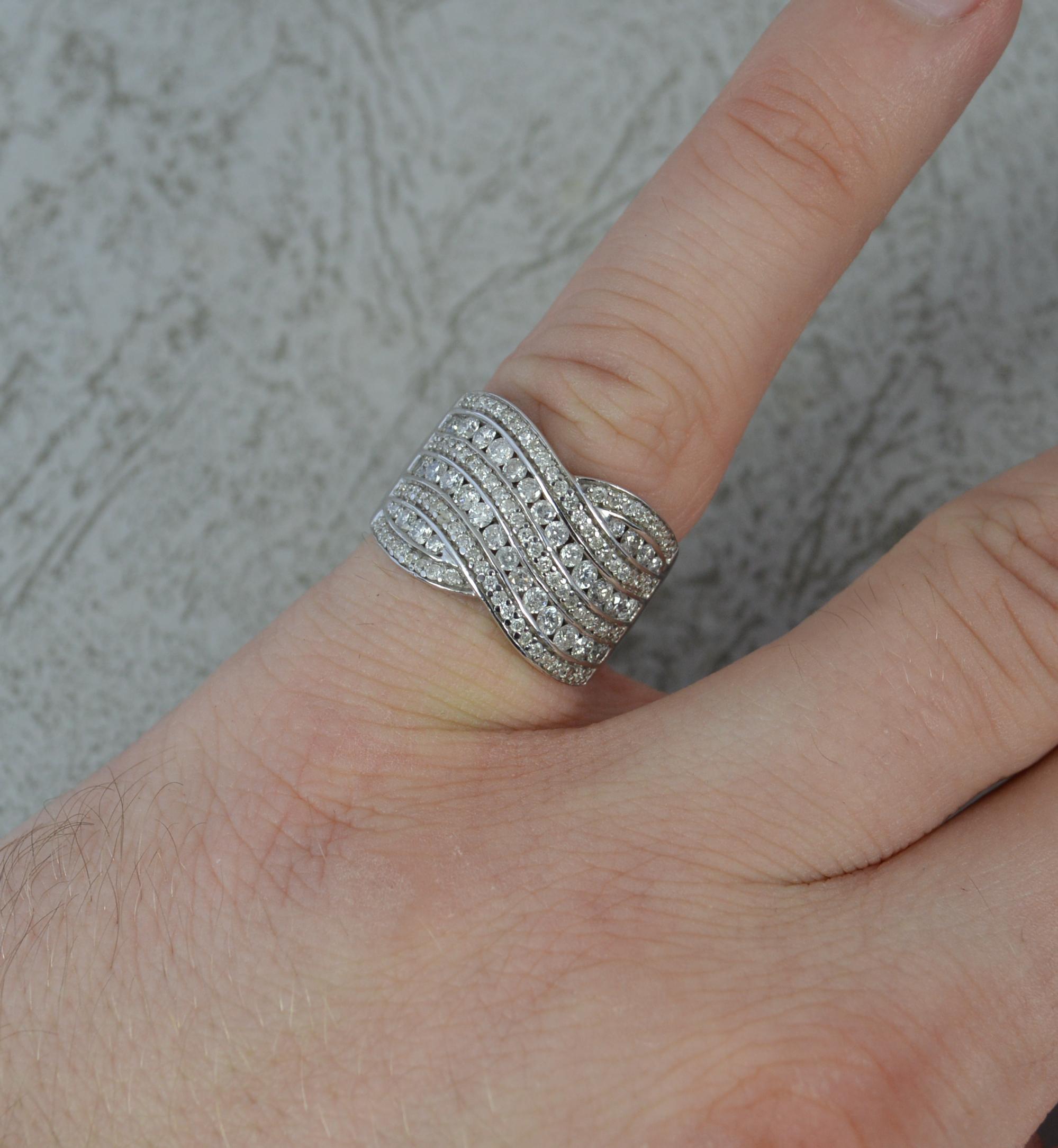 A rather unusual contemporary ring.
Solid 18 carat white gold example. Good, solid example.
Set with many round brilliant cut diamonds forming a large crossover cluster band.
18mm x 13mm cluster head.
​
CONDITION ; Very good. Well made example. Well
