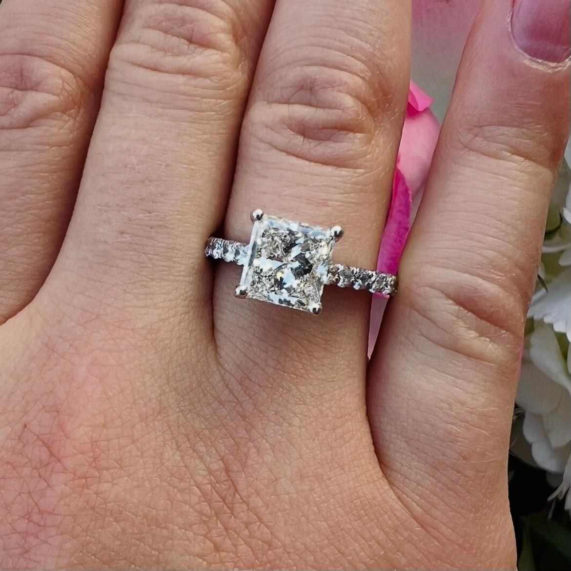 Truly a ring fit for a princess! This 14 karat white gold beauty features a 1.89 carat Natural Princess Cut diamond ring set in a 4-prong setting with 14 natural round diamonds expertly set within the ring shank for an additional 0.42 carats. The