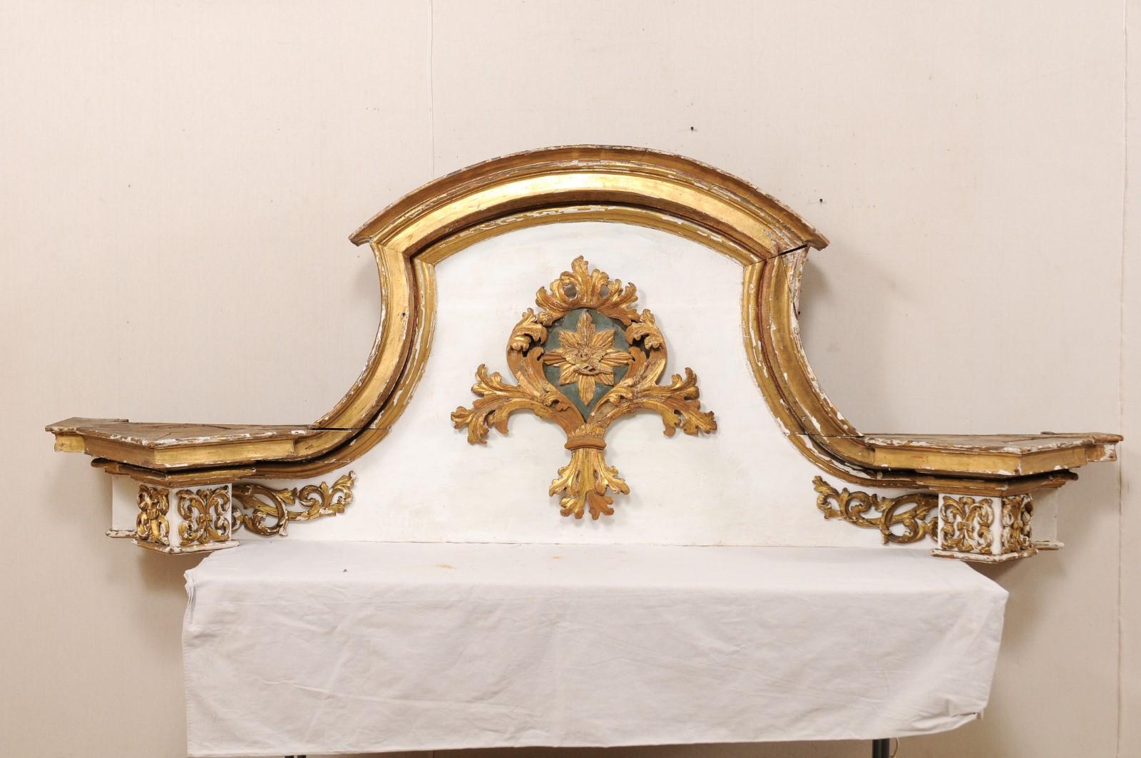 An Italian 18th century grand-scale gilded and painted wood pediment fragment. This antique architectural fragment from Italy has a greatly spanning width of over 8.75 feet, with a height at center of over 3 feet tall. There is a heavily molded