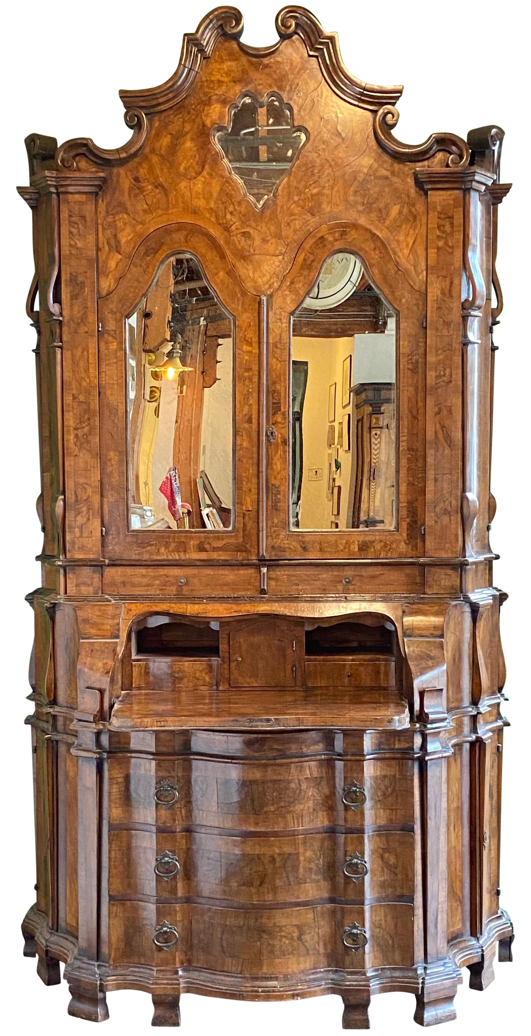 An impressive and unusually tall Venetian black walnut and burled walnut secretary. The mirrored top cabinet doors opening to reveal a multi drawer fitted interior, having a drop front writing surface over three drawers.
Beautiful color walnut