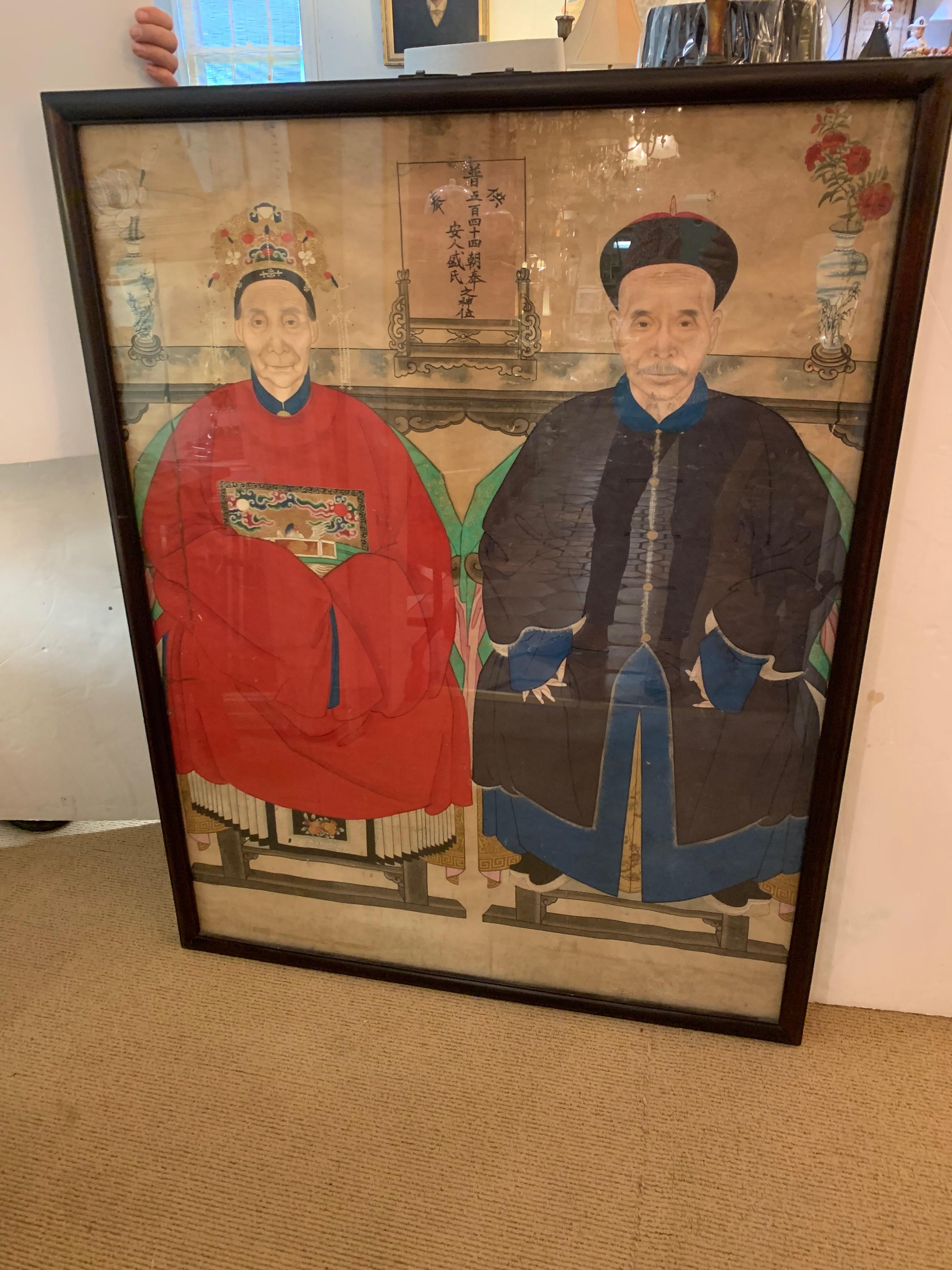 Very large and meticulously detailed Chinese ancestral portrait of a royal man and woman in red and navy blue robes against a neutral off white background. Wonderful Chinese lettering, a blue and white vase, and long beautifully rendered fingernails