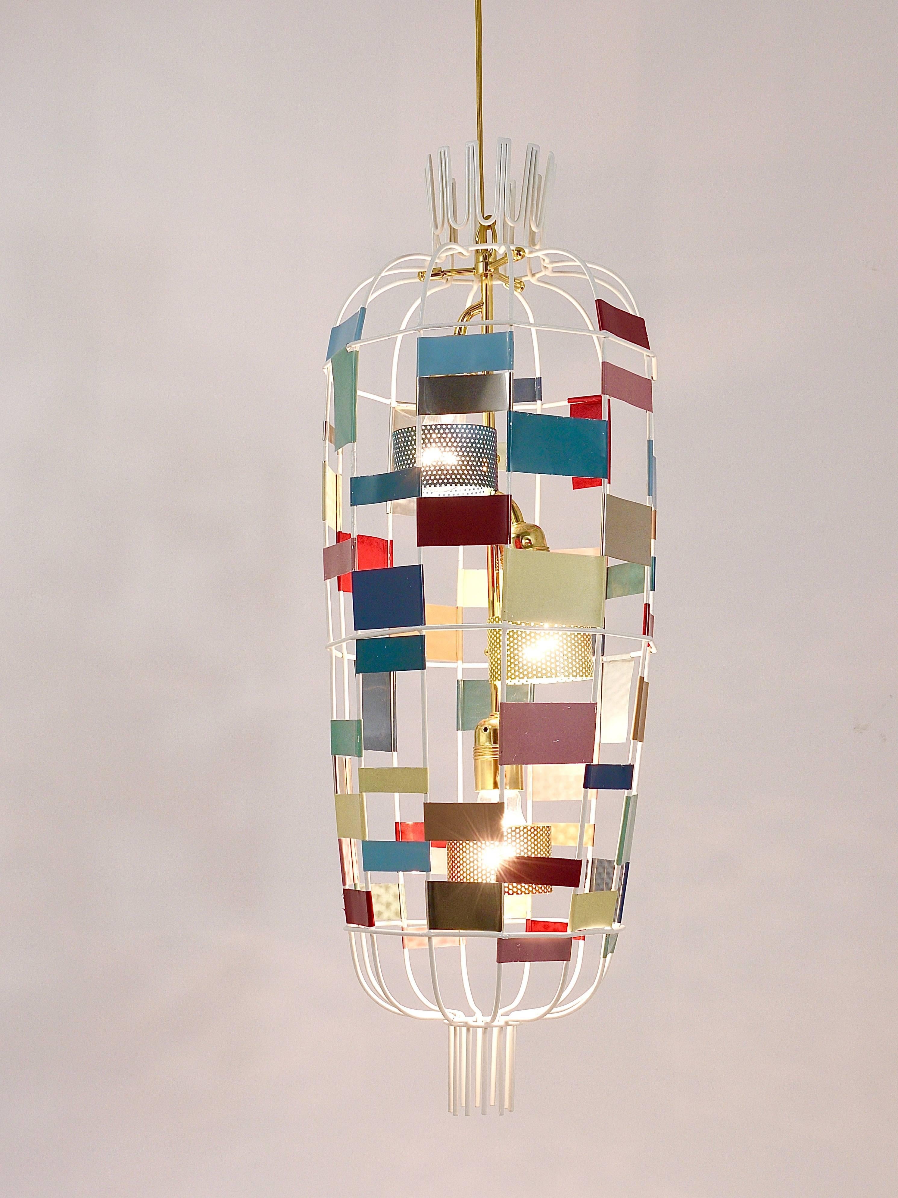 A charming Mid-Century Modern French chandelier / pendant light from the 1950s in the style of Jacques Biny / Luminalite. Multicolored square metal sheets in different sizes on a white metal corpus with a lot of beautiful brass details, like little