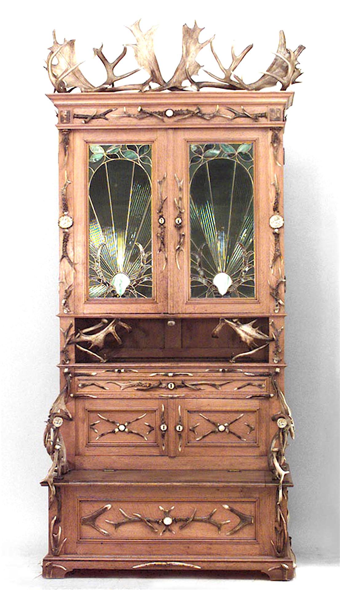 Rustic German (19th Century) oak cabinet with horn trim & carved medallions with flip seat bench base and upper section with 2 large stained glass doors and 2 smaller doors.
 