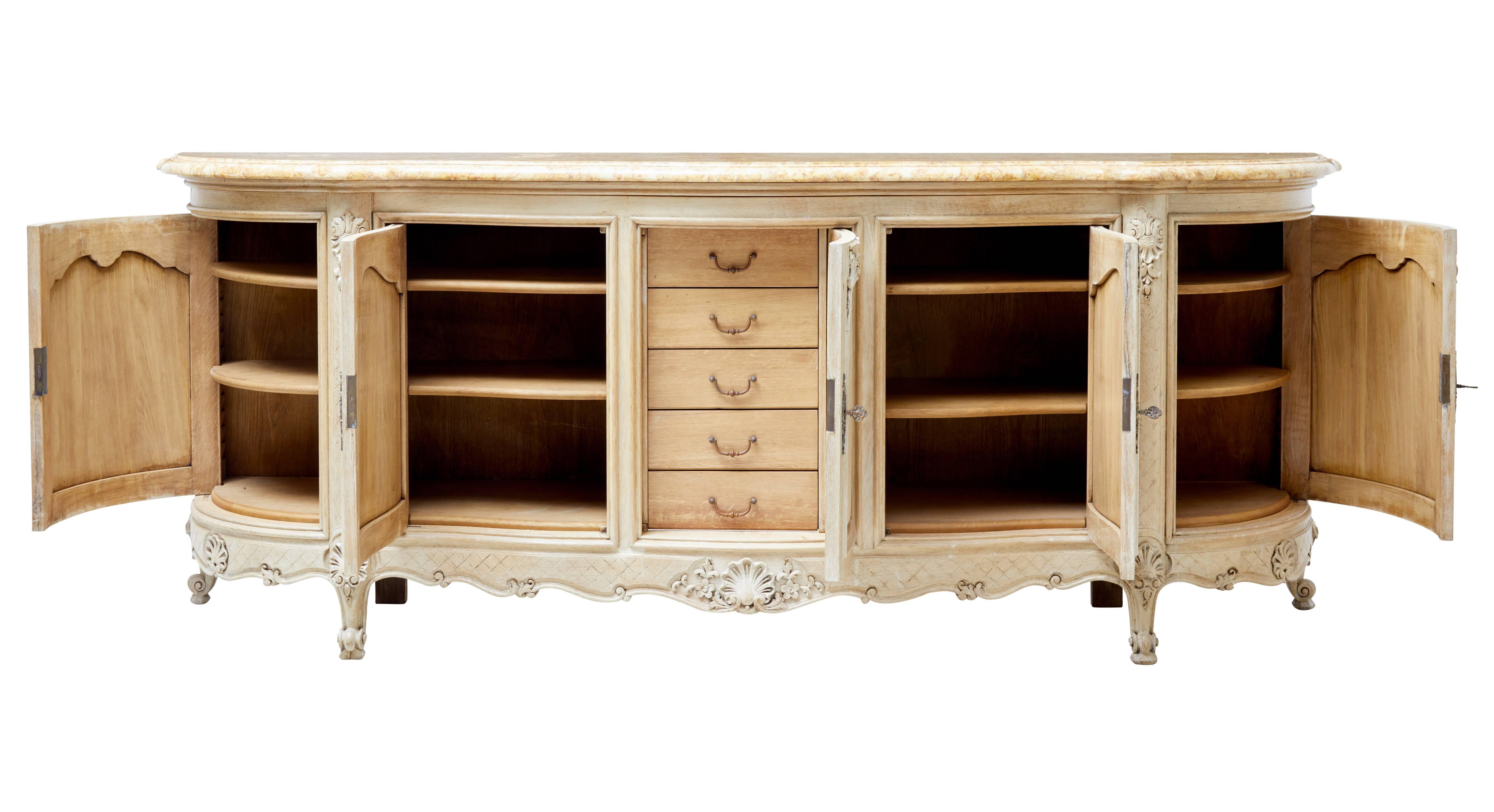 Fine quality serpentine shaped oak sideboard of large proportions.

Presented in a stripped oak finish, with original marble top.

Five doors to the front, middle door opening to reveal a fitted interior of five drawers, flanked either side by