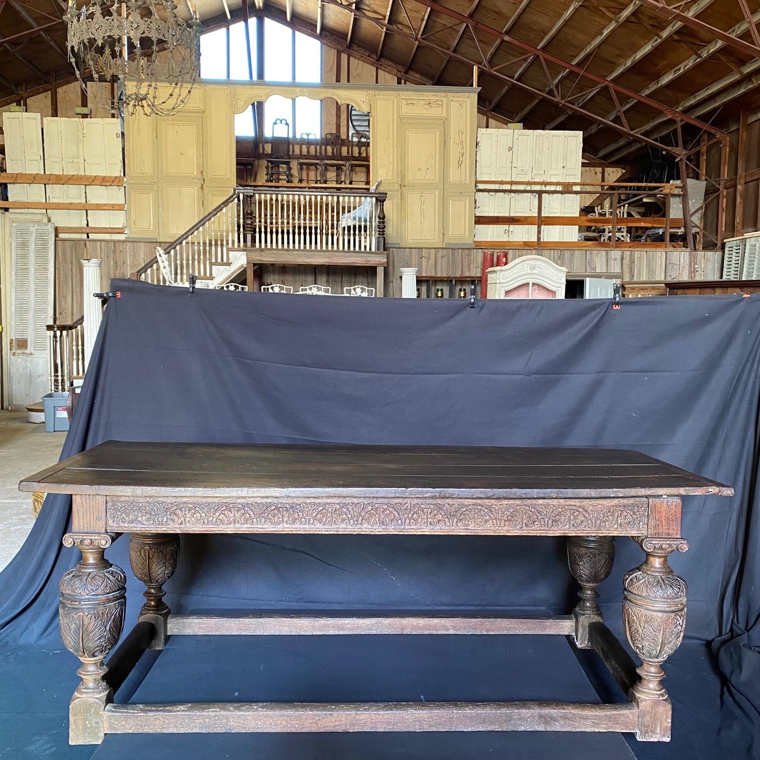 An impressive fine quality solid oak refectory table of unusually long proportions having solid planked oak top above four boldly gadrooned turned and carved legs with bulbous cup and cover supports, each with Corinthian capitals and united with
