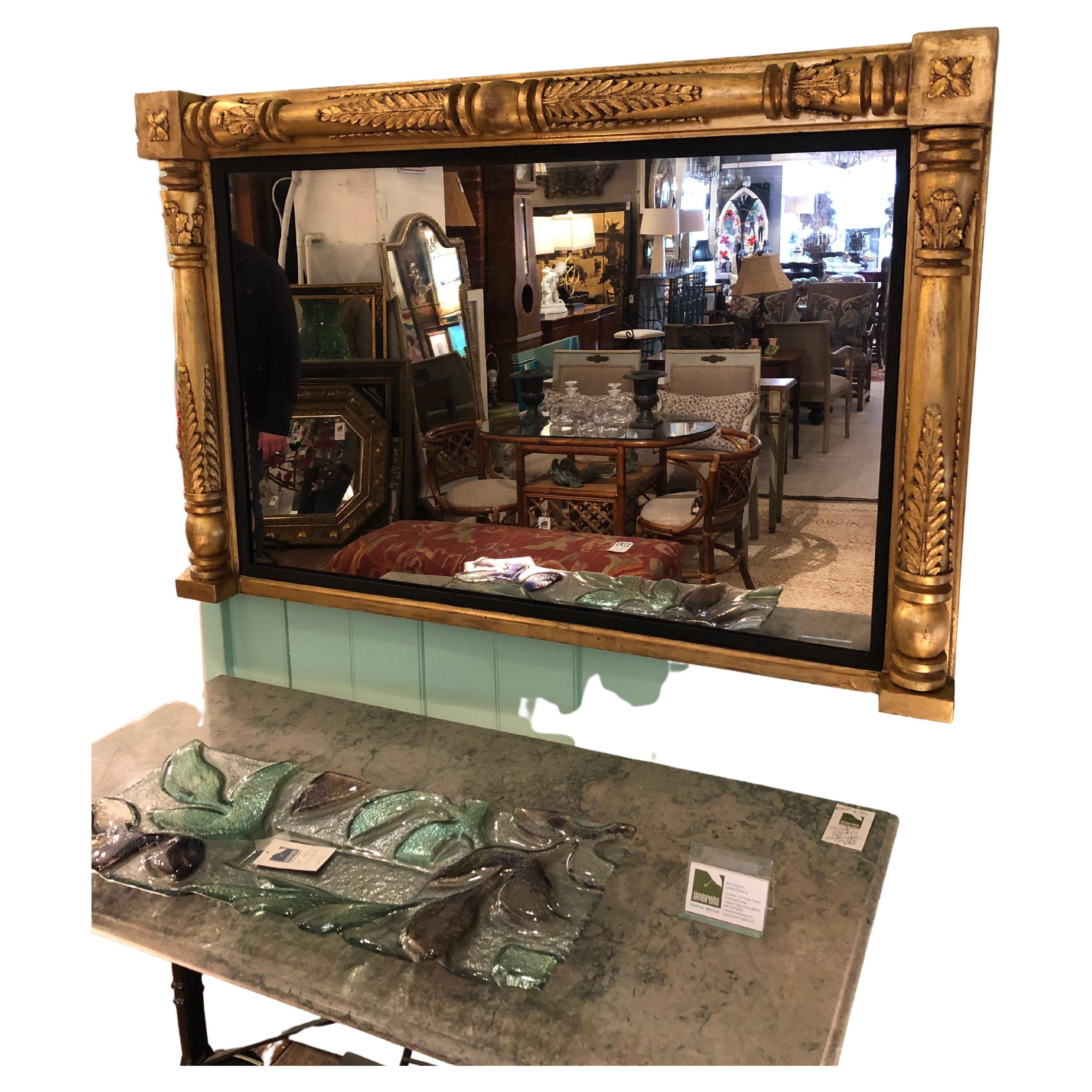 Impressive chunky giltwood horizontal mantel mirror having gutsy carved frame, interior black filet and mirror that measures 41.25 x 26

Orr.