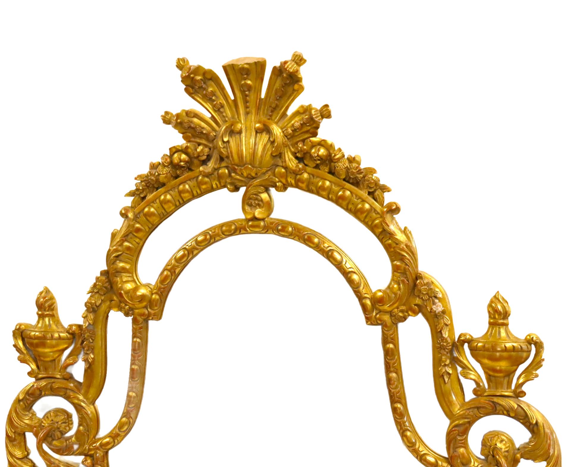 Cet exquis miroir en bois doré sculpté à la main, fabriqué en Italie au milieu du XIXe siècle, est un remarquable exemple d'art décoratif. Le cadre est orné de motifs floraux et de plumes complexes, complétés par d'élégants fleurons en forme d'urne,