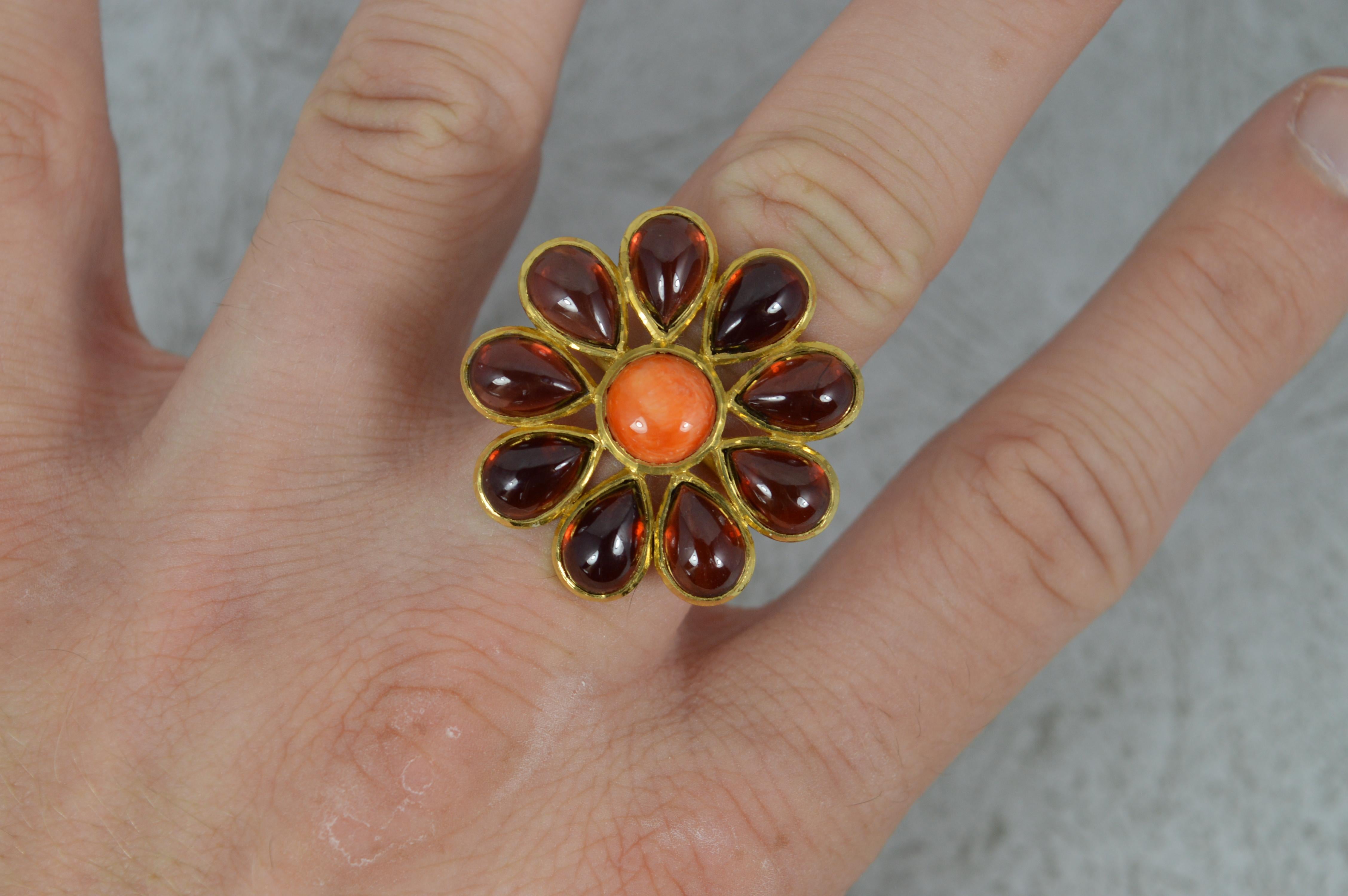 A beautiful statement ring.
Solid 22 carat yellow gold example.
Designed with a circular coral to centre, 8mm diameter. Surrounding are nine pear shaped garnet cabochon stones, each 6mm x 8mm.
Creating a statement cluster head of 29mm x 29mm and