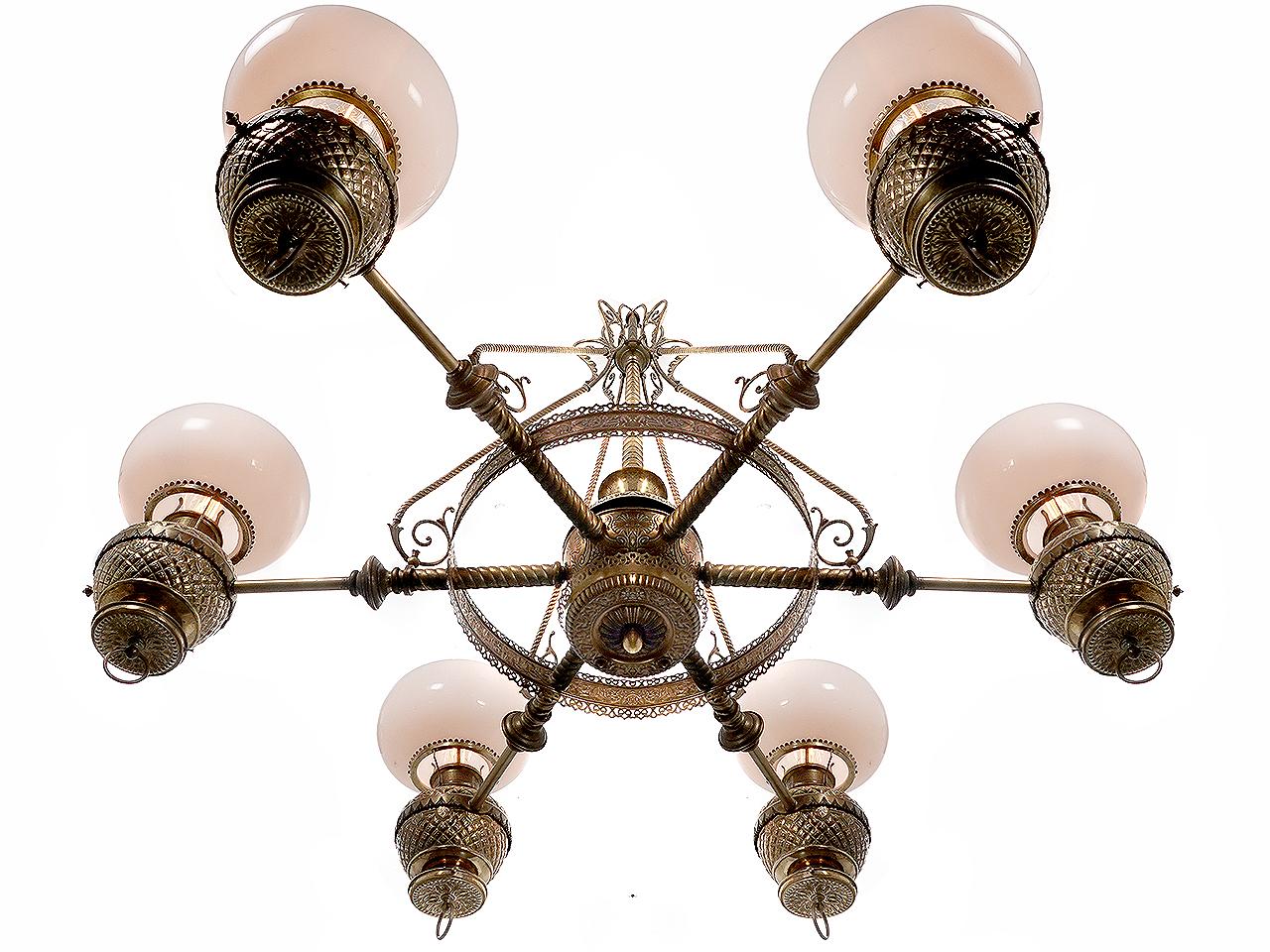 With a 54 inch diameter and 6 complete highly decorative oil lamps this chandelier presents itself as a very impressive fixture. Note the 6 original bun shaped milk glass outer shades. If you are looking to make an important statement This lamp is