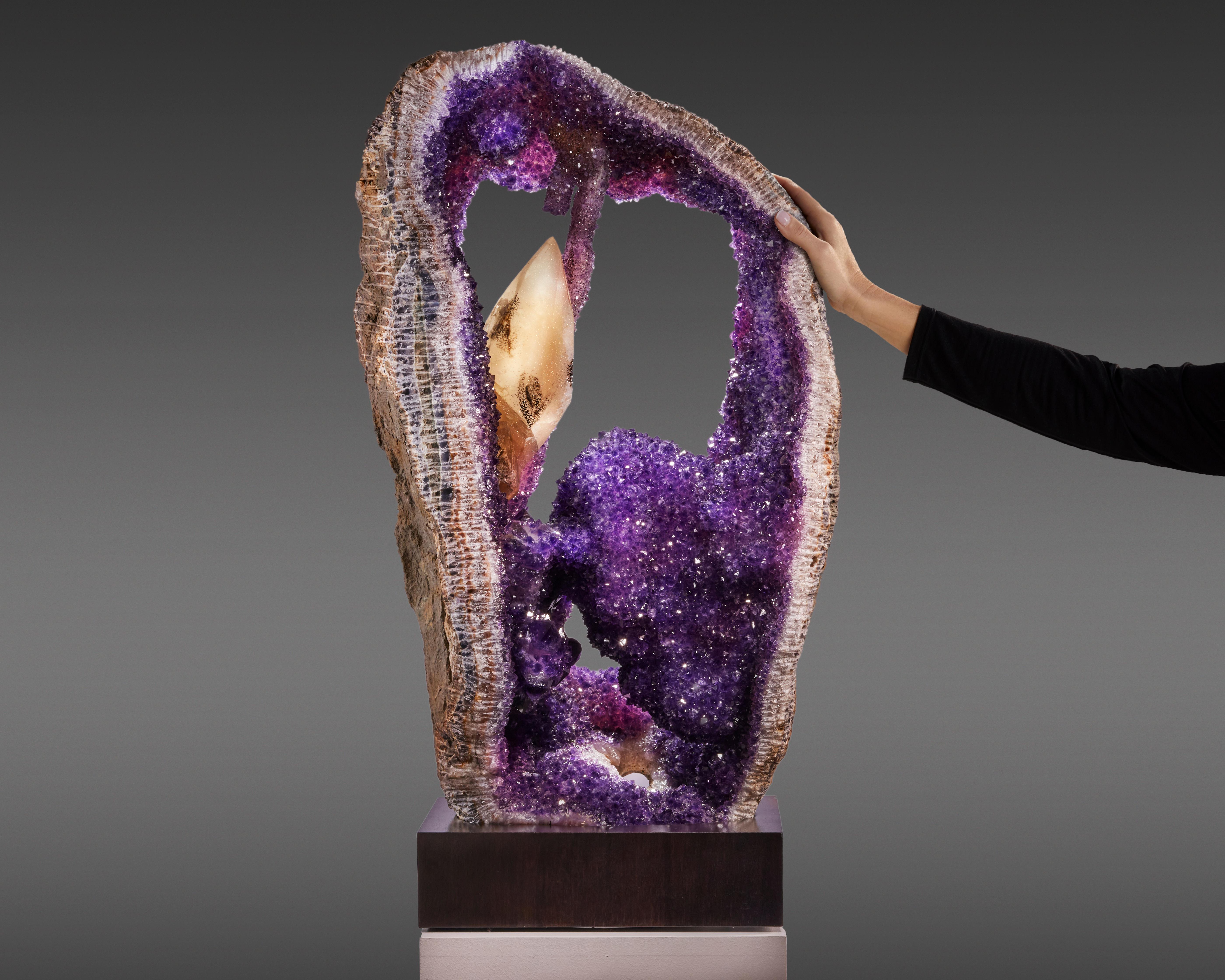 Magnificent Amethyst geode, a captivating treasure with a heart of intense purple and a unique large calcite, cradled in a custom rotating stand for a 360-degree view of its splendour.
This piece is distinguished by a striking Calcite crystal,