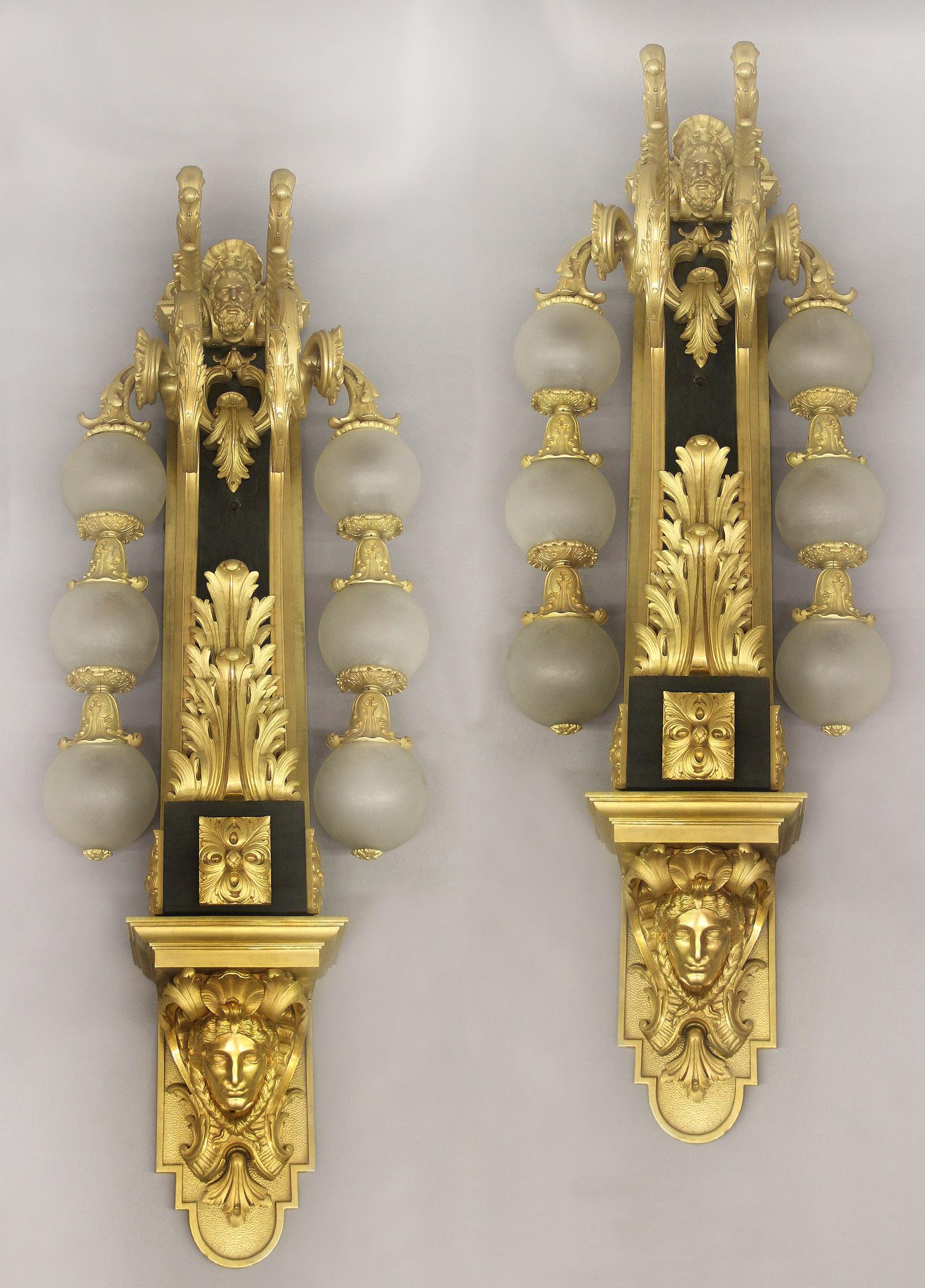 An Impressive and Imposing Pair of Early 20th Century Gilt Bronze Six Light Sconces

The long body topped and centered with a mask of Hercules, above C scrolled acanthus branches, two arms with three round frosted lit globes run down the sides,