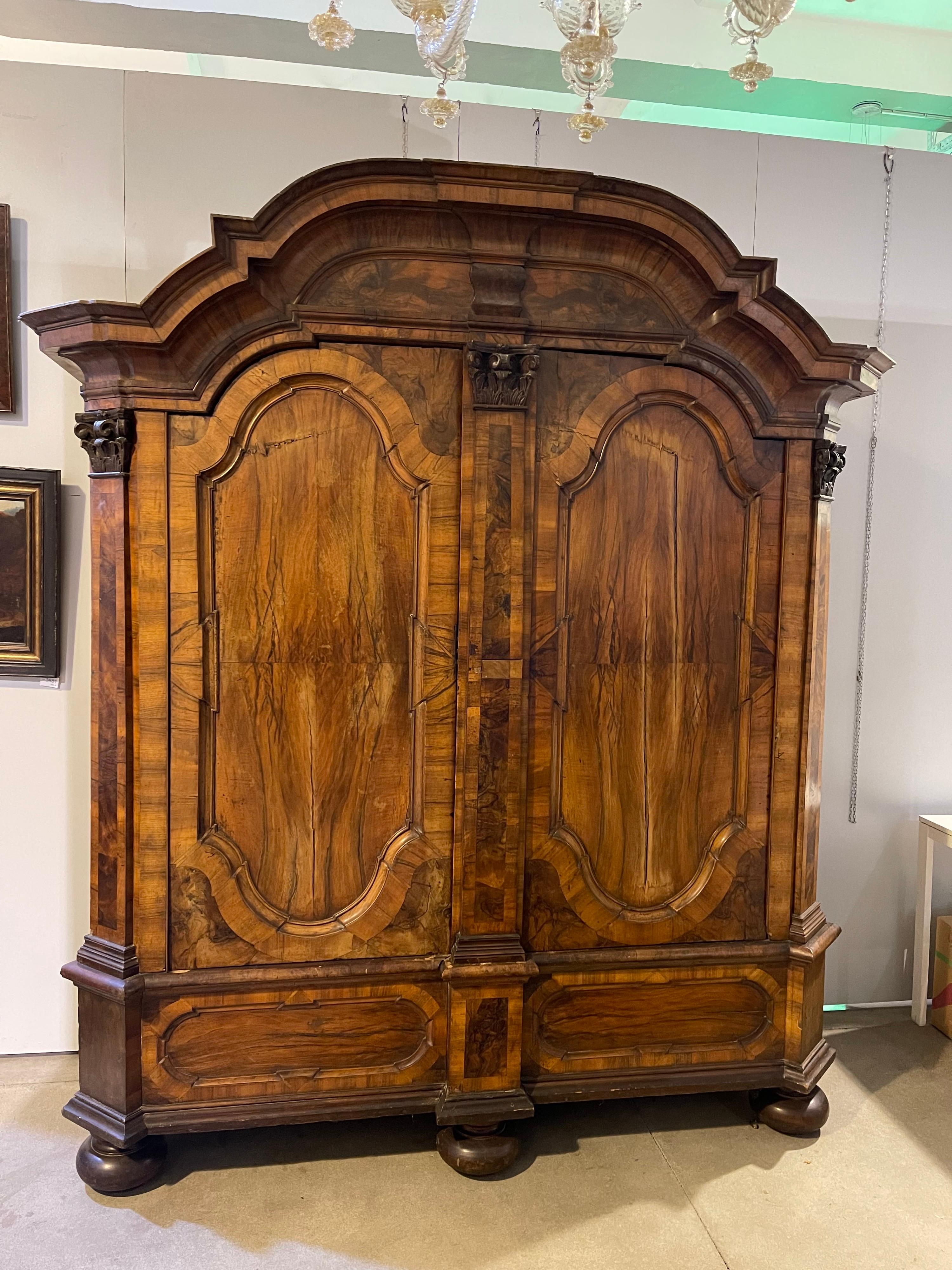 Walnut, veneered on oak. High, two-door body with panels and half-columns with carved capitals, on ball feet. Profiled gable wreath. Original iron box lock without key. Signs of age and use. Probably West Germany in Mainz, mid-18th century. Approx.