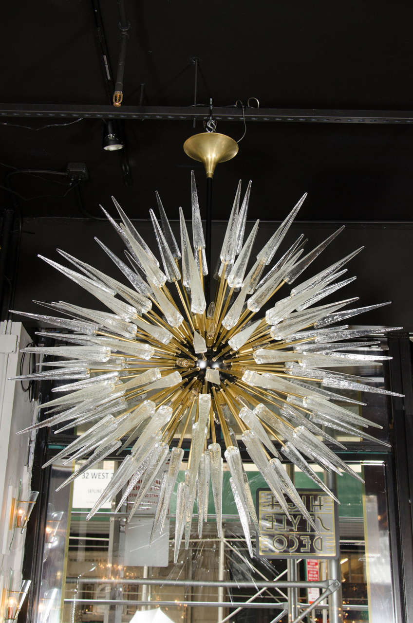 Impressive and monumental spiked Sputnik chandelier that features a black enamel center that boosts 24 candelabra based bulbs. This chandelier has numerous brass rods that emanate from its black enamel center with each brass rod being capped with a