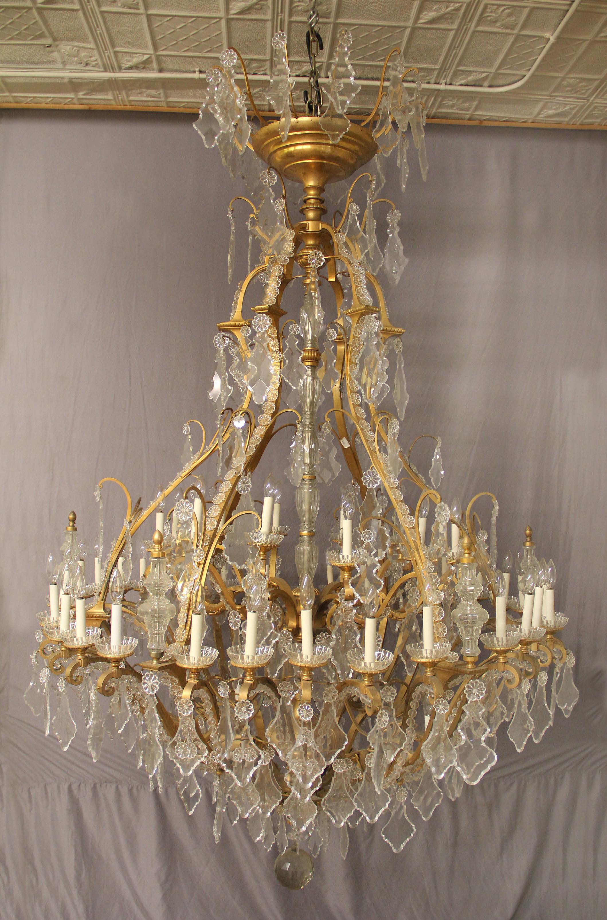 A Very Impressive and Palatial Late 19th Century Gilt Bronze and Cut Crystal Forty Eight light chandelier

The large cage chandelier with multi-faceted and shaped crystals, beaded arms, cut crystal central column leading down to a large gilt bronze