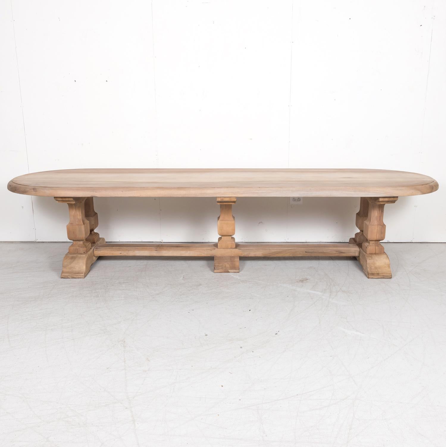 A large antique French trestle dining table, handcrafted of solid walnut by skilled artisans near Saint-Rémy-de-Provence in the South of France, circa 1920s. Having a bleached or washed finish, this impressive Provençal trestle table has a 2.75