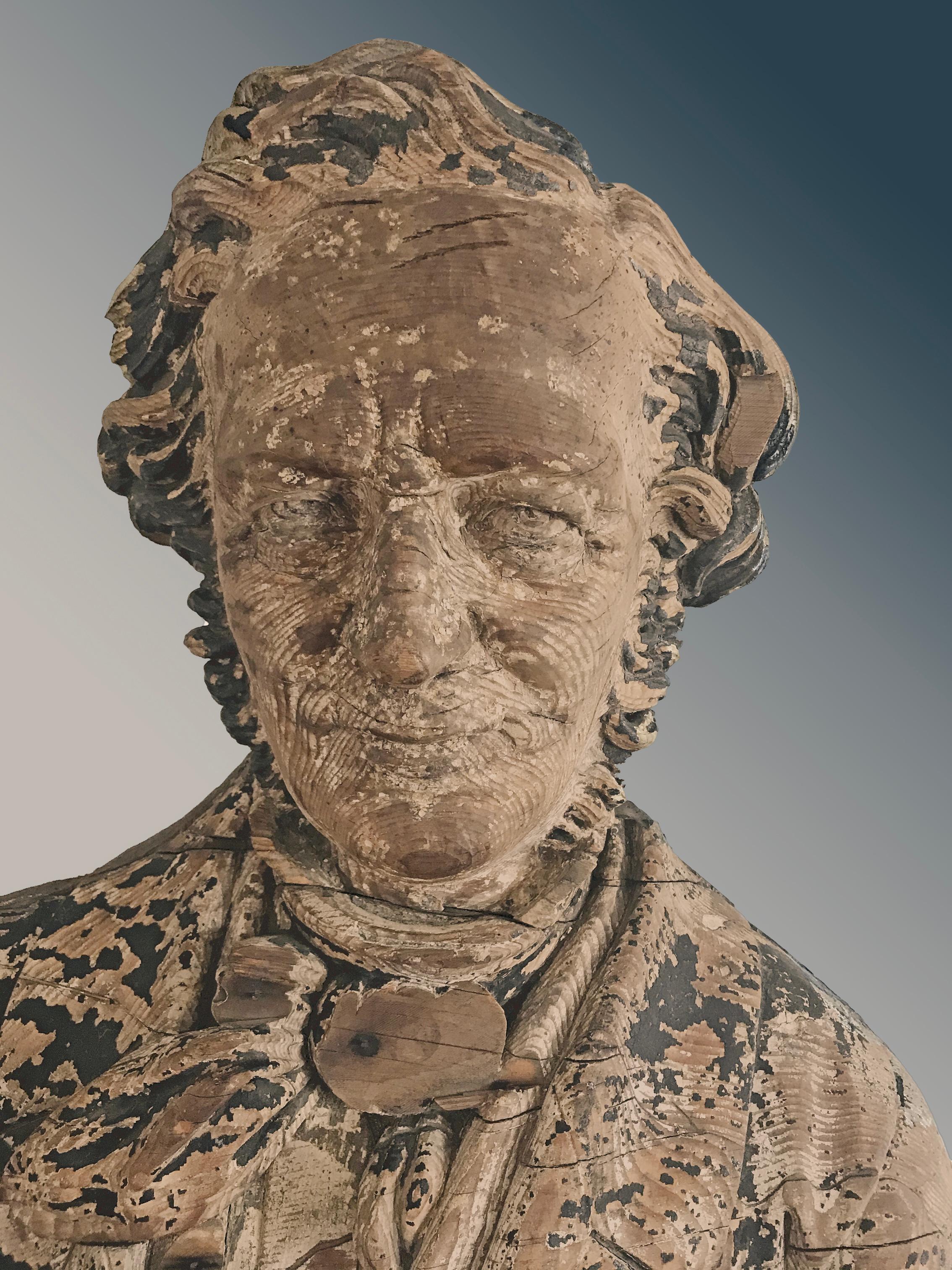 Sternboard carving of a bust, carved in the round, wearing a blue-painted jacket and black tie, with an undershirt. Decorated sternboard carvings were a rarely used counterpart of figureheads, usually they were eagles or some type of decorative