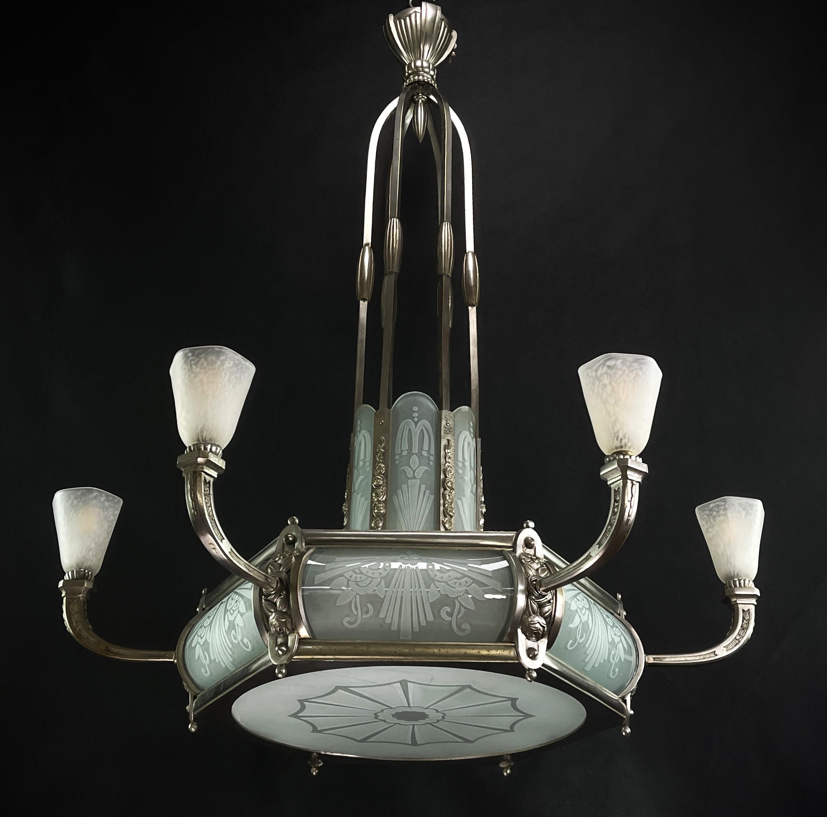 Art-Déco-Kronleuchter 

Dieser atemberaubende Art-déco-Kronleuchter aus den 1930er Jahren ist ein herausragendes Beispiel für die Eleganz und Raffinesse des Art-déco-Stils. Mit seiner Kombination aus Metall und Glas verkörpert dieser Kronleuchter