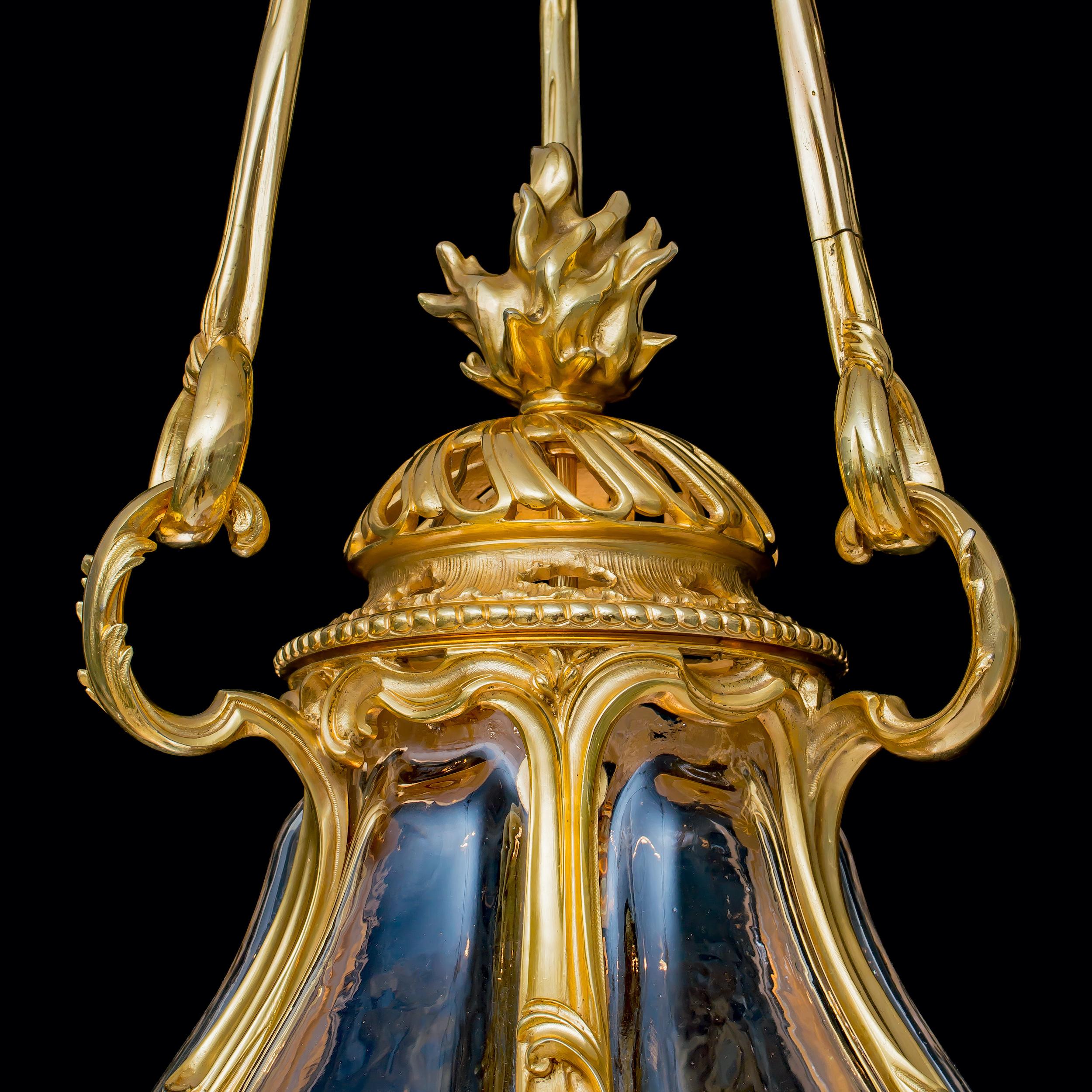An Important Lantern
In the Louis XV Manner

Constructed in gilt bronze, the ovoid body composed of six blown crystal facets interspersed with ormolu acanthus-stylized scrolls, the lower and upper registers with openwork bronzework of Vitruvian