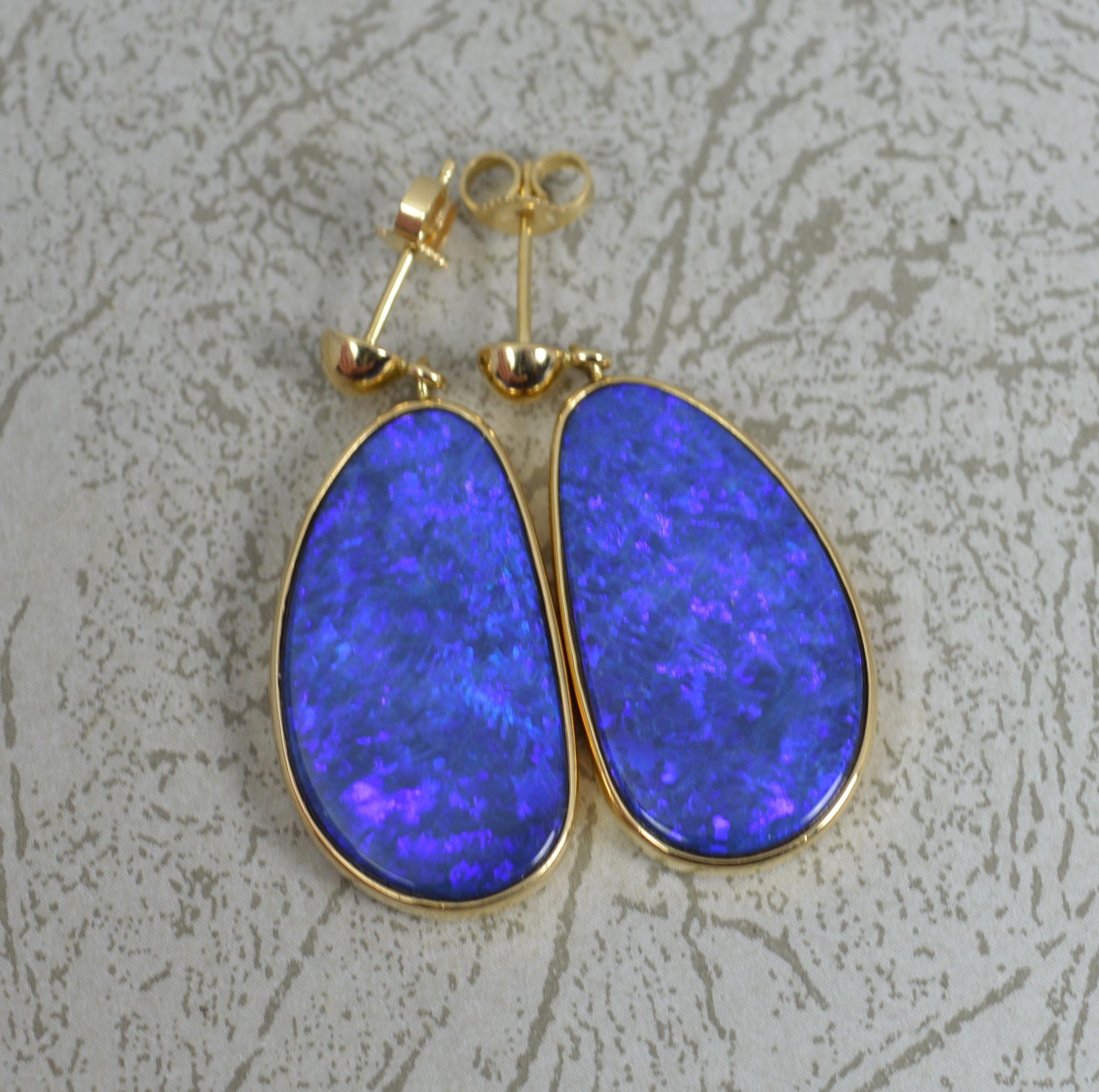 A beautiful pair of ladies 14 carat yellow gold and opal doublet earrings. 
Butterfly backs on post with a single drop dangle amber to each.
Very large single black opal doublet stones, very colourful with strong blue undertone. In fine bezel