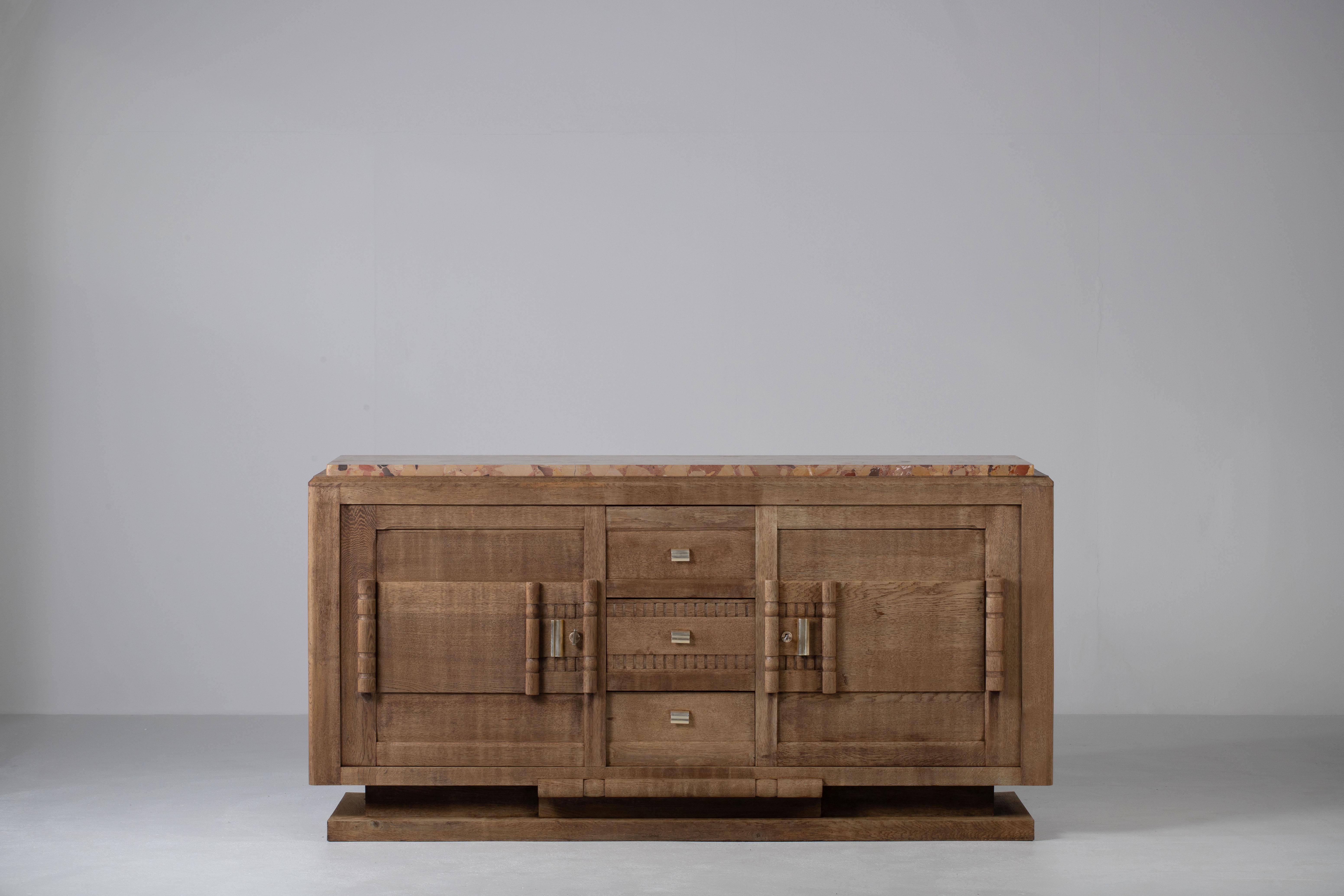 Credenza, solid oak, France, 1940s, after Charles Dudouyt.
Large Art Deco Brutalist sideboard. 
The credenza consists of three central drawers and two storage facilities and covered with very detailed designed door handles. 
This buffet features
