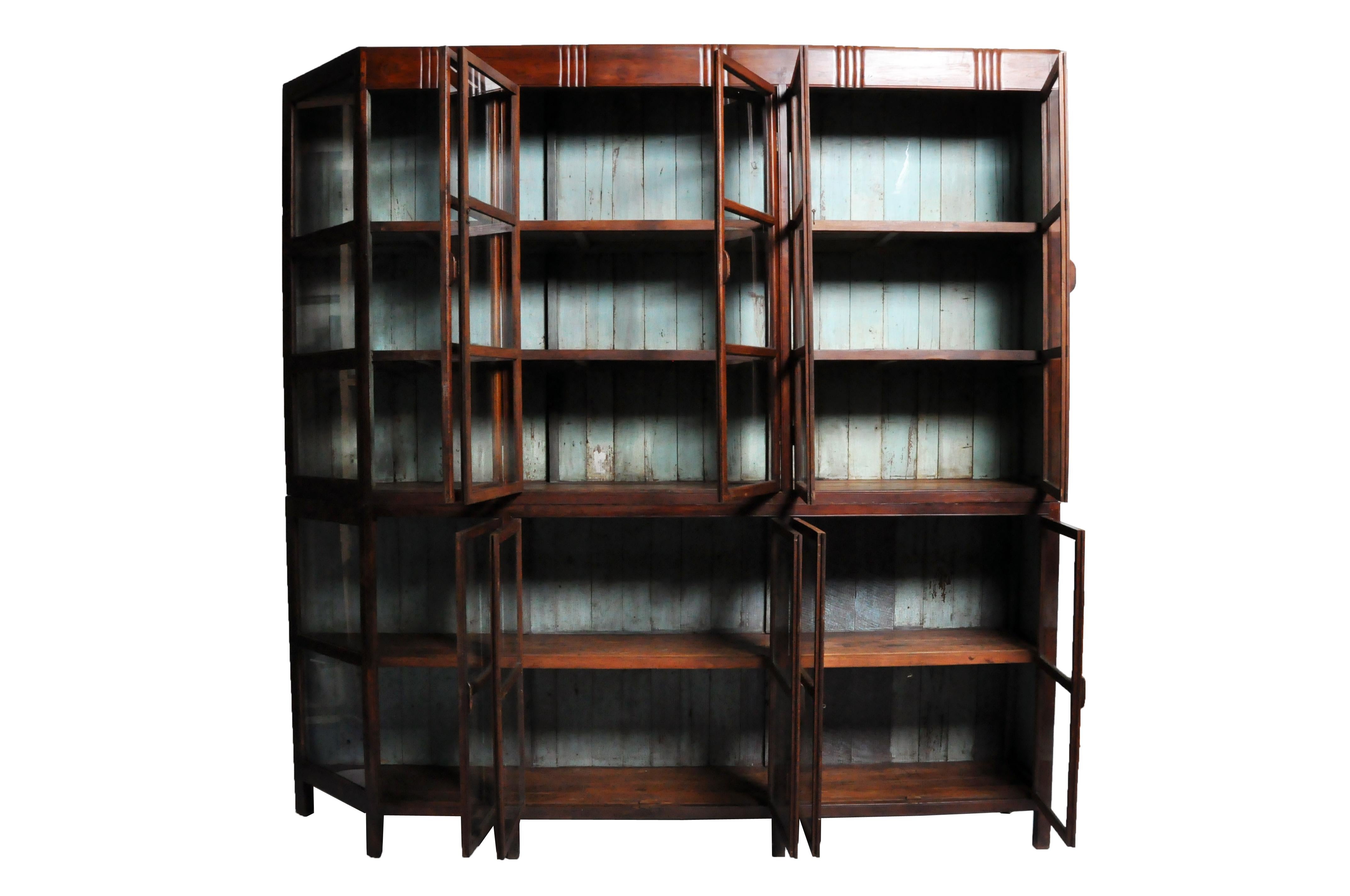 This handsome British Colonial cabinet comes in two parts, the top having a 5 glass doors that open up to shelves for ample storage over another set of 5 glass doors with additional shelves. Both open to compartments lined with shelves. Beautiful