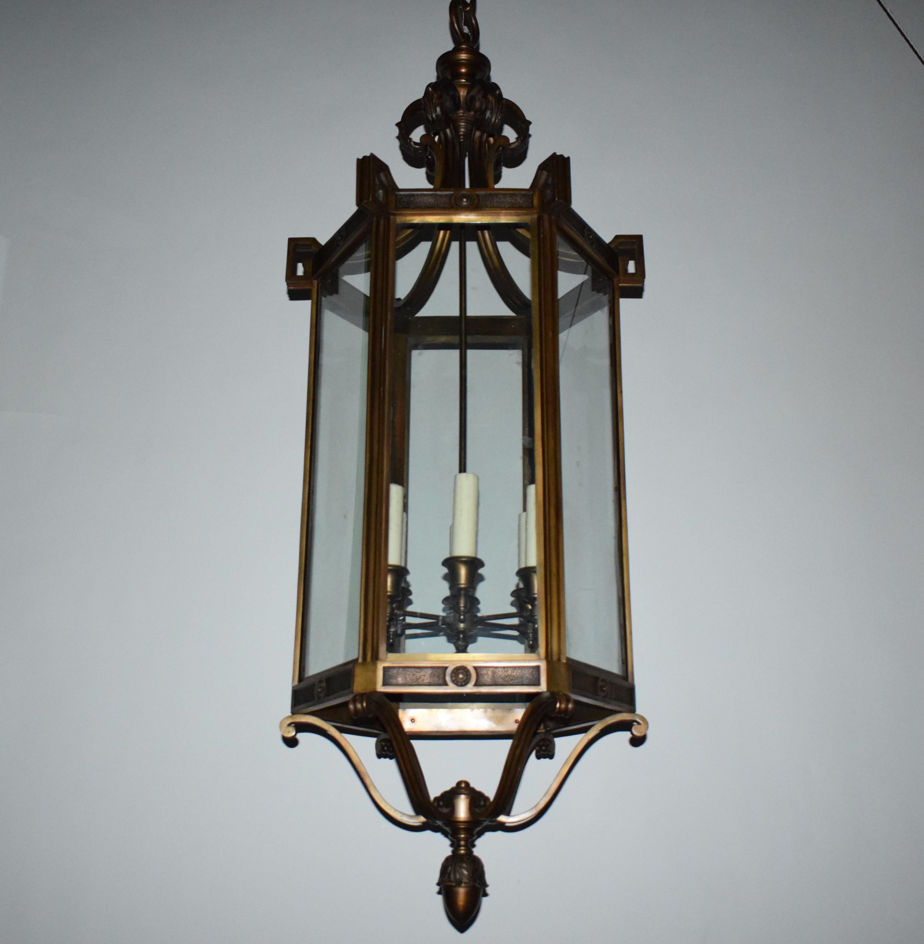 A magnificent bronze lantern attributed to E. F. Caldwell. Hexagonal in shape with beveled glass panels supported at the top by six brackets ending in Greek keys. At the bottom six 