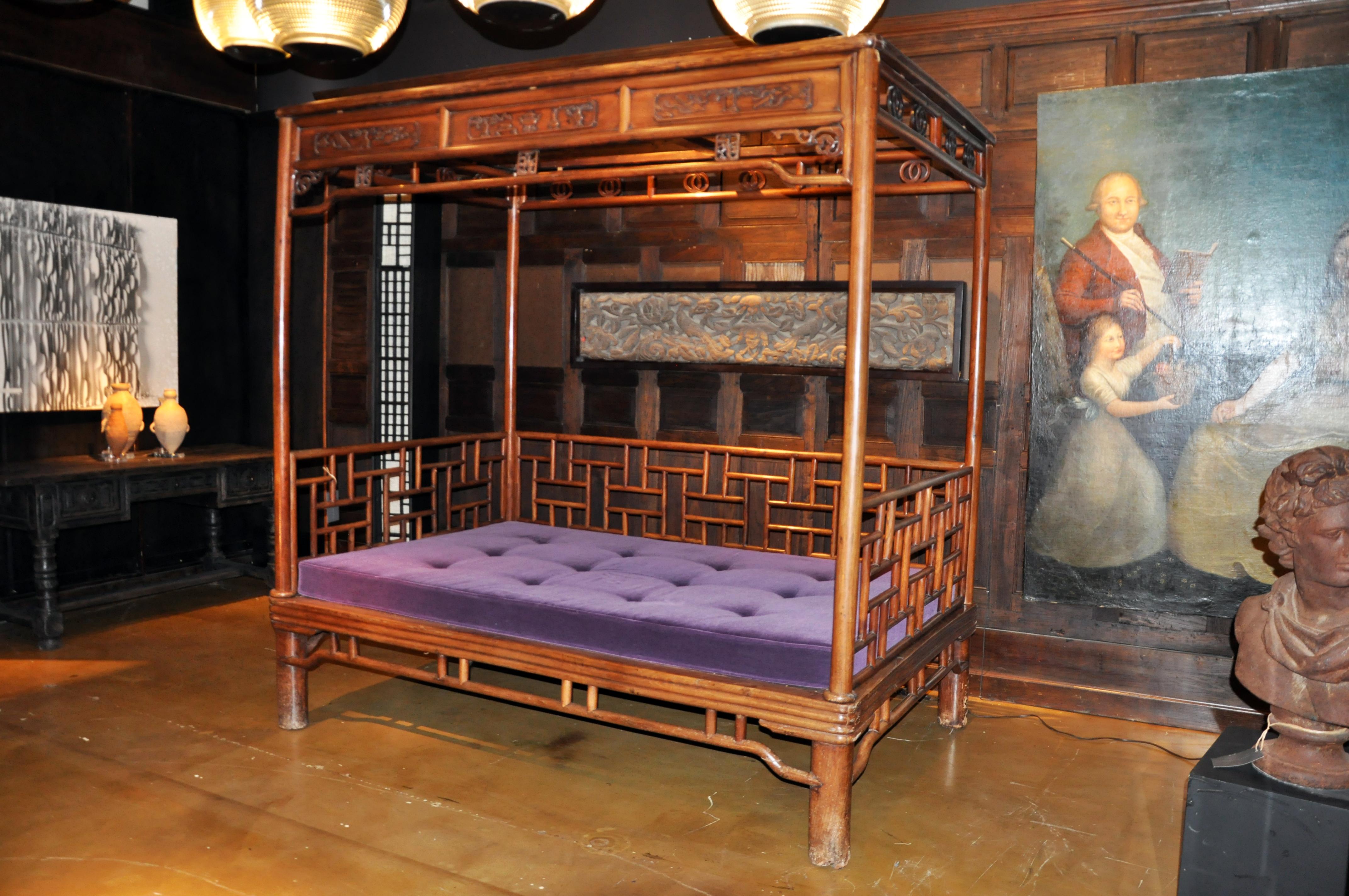 This traditional daybed dates to the early 1800s and is made from Ju Mu Wood (Southern Elm). It has a traditional Mingy Dynasty style with rounded-post canopy and bamboo-form bed frame. The jute cord webbing and woven rattan seating surface has been